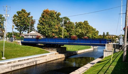 Iconic blue swing bridge over the Trent-Severn Waterway in Bobcaygeon, surrounded by lush greenery and a clear autumn sky.
