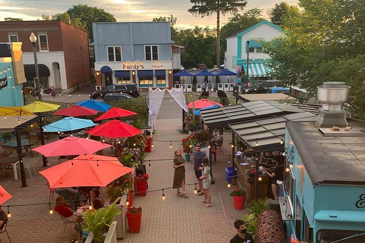 A lively patio scene in downtown Bobcaygeon with colourful umbrellas, food stalls, and locals enjoying a summer evening.