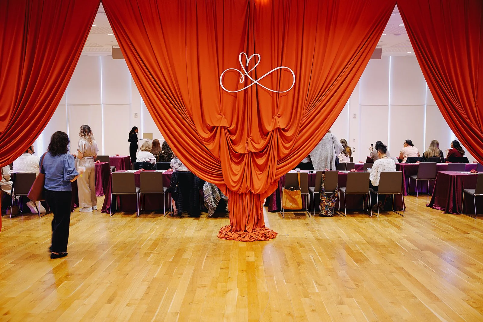 Collective Vow conference stage framed by red draping and the heart-infinity logo.