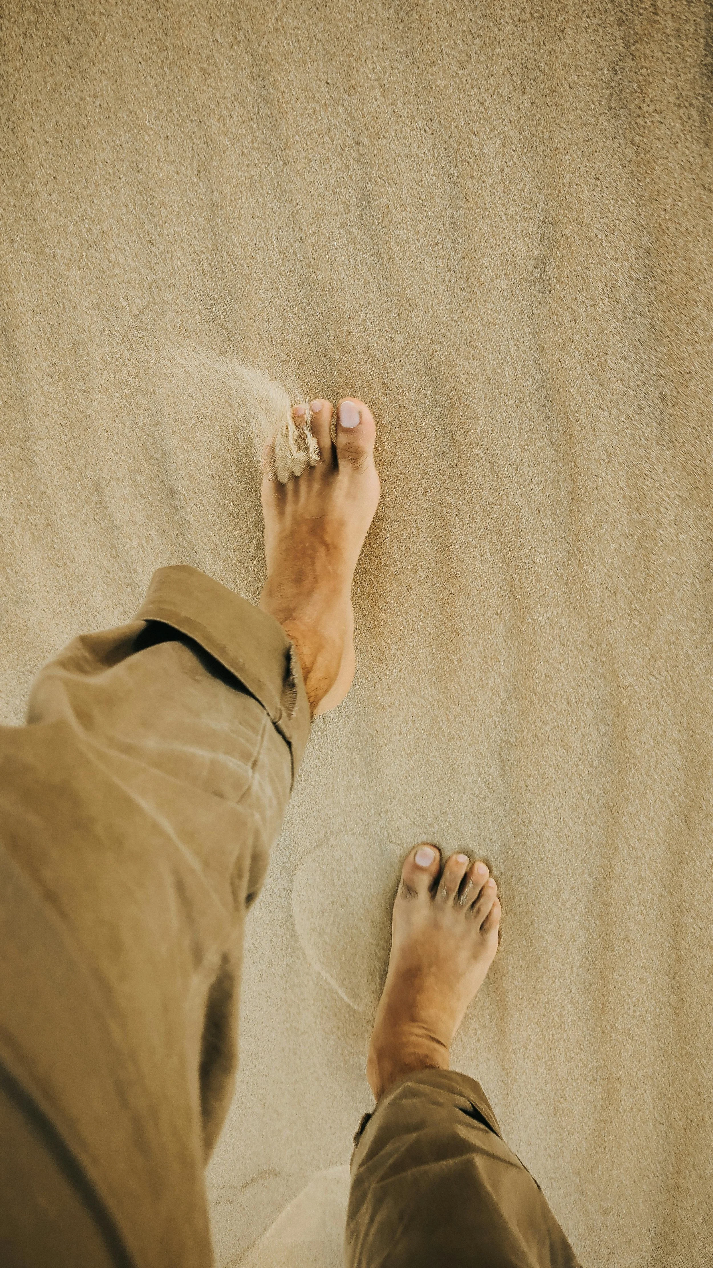 Walking barefoot on sandy beach with visible sand dunes.