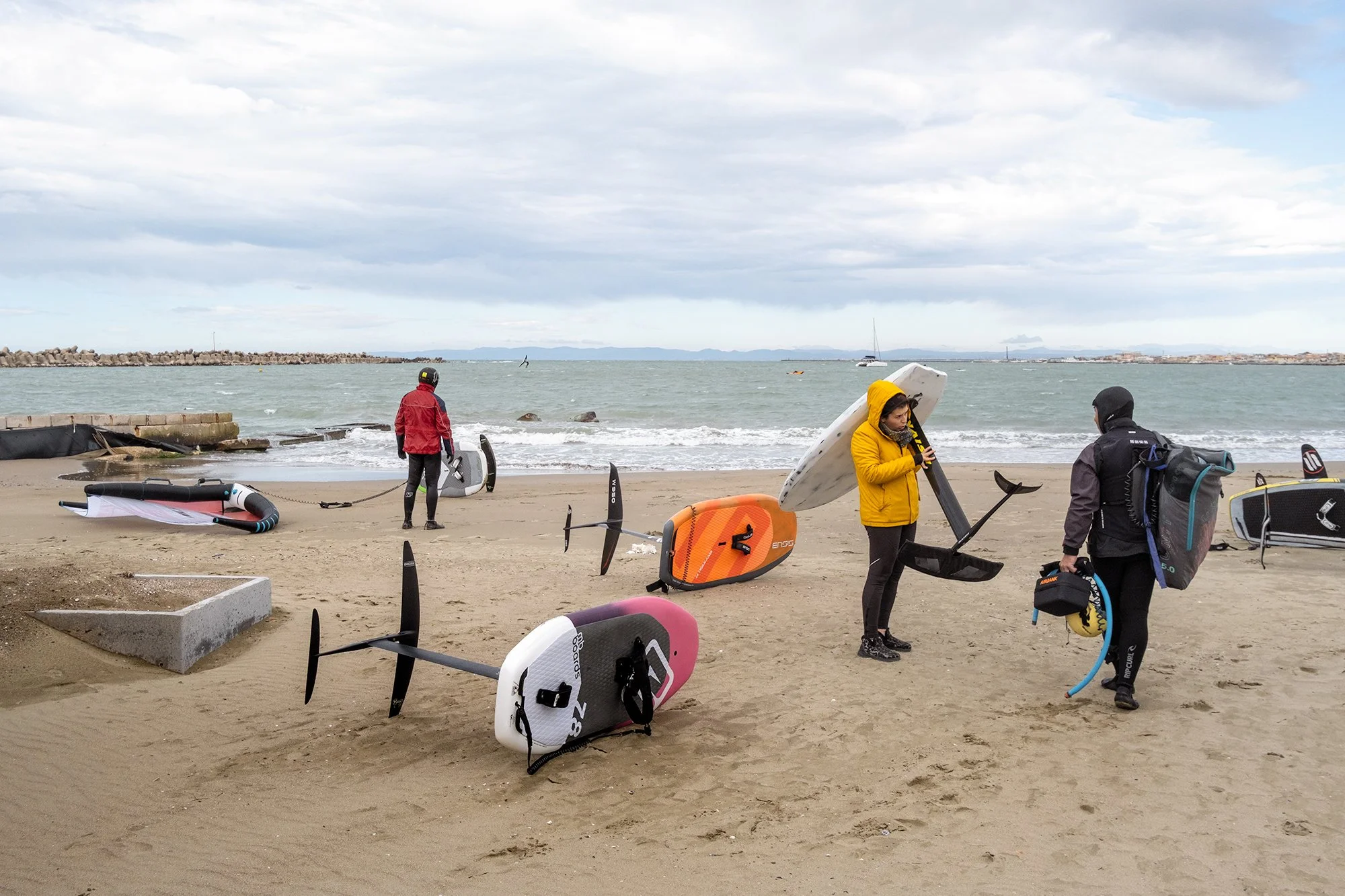 Surfers entering the water, construction site area, 2024