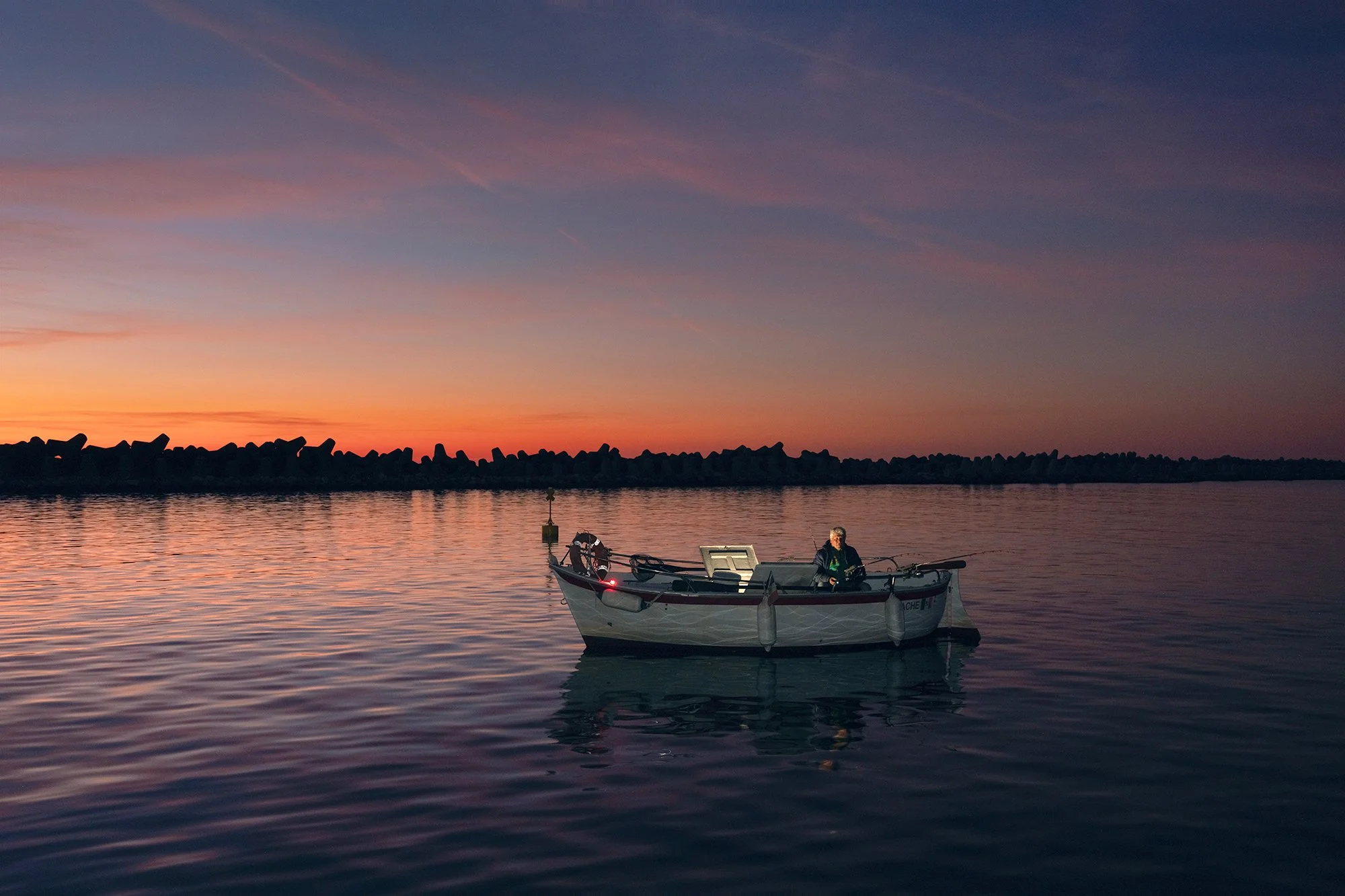 Alberto heading out for a night fishing trip; in the background, the breakwaters installed during the initial port construction, 2025