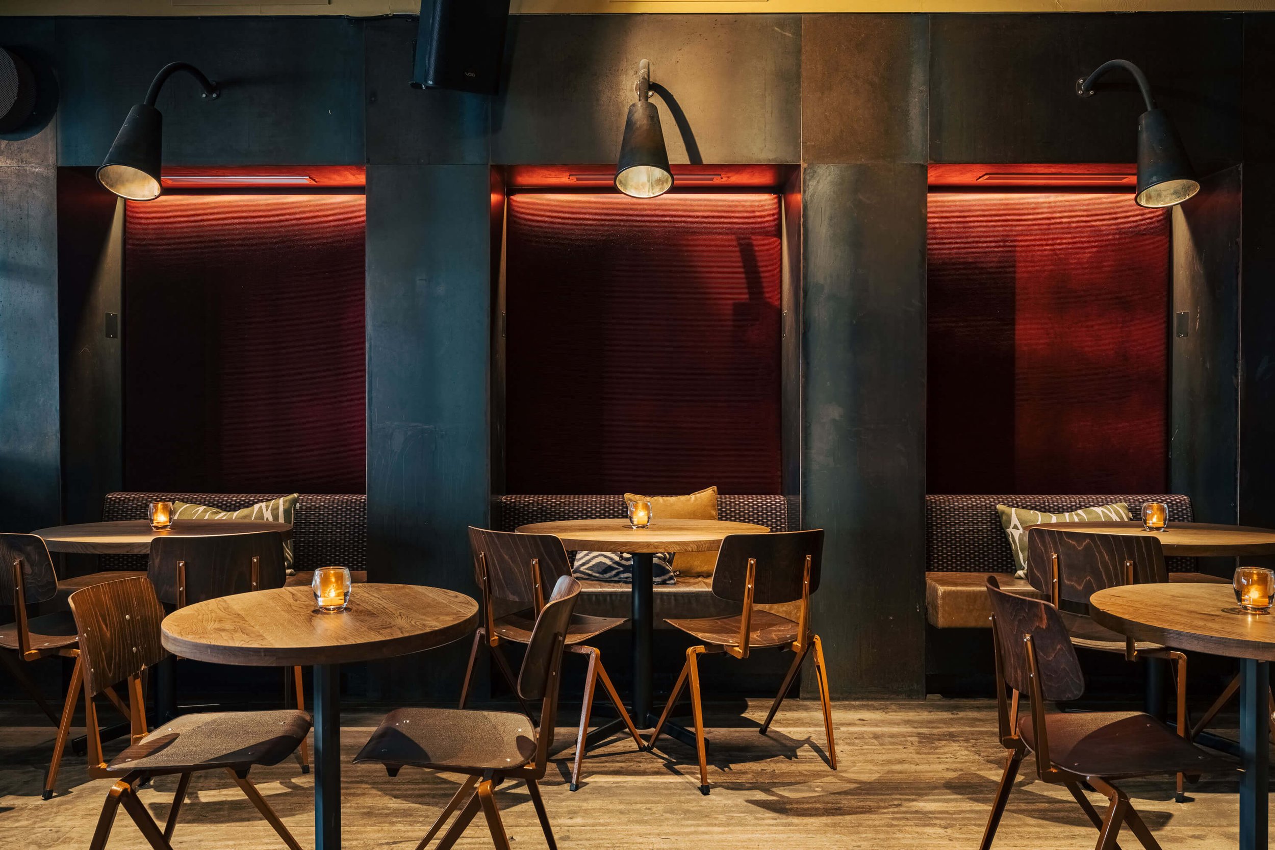 Interieur van een sfeervol café met houten tafels, stoelen en gezellige lampjes.