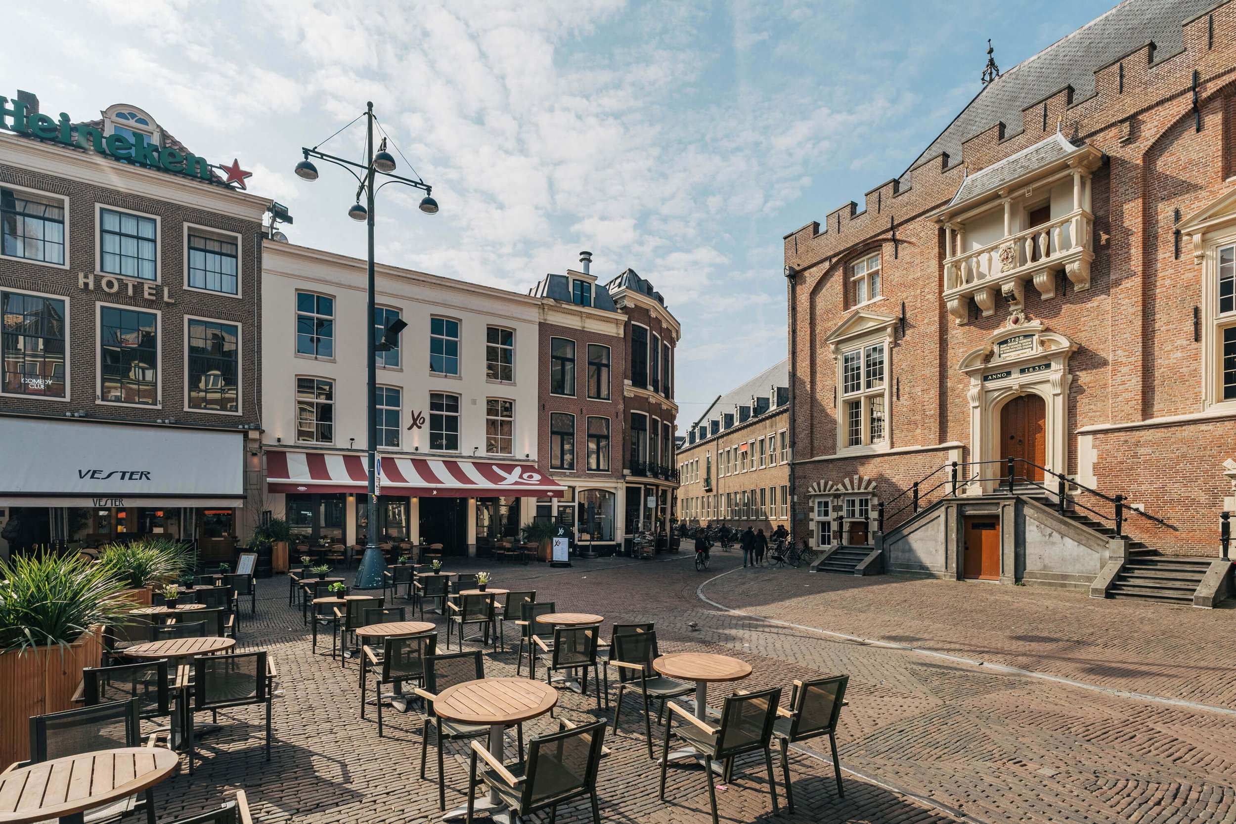 Plein met terras, historische gebouwen, baksteen en ramen.