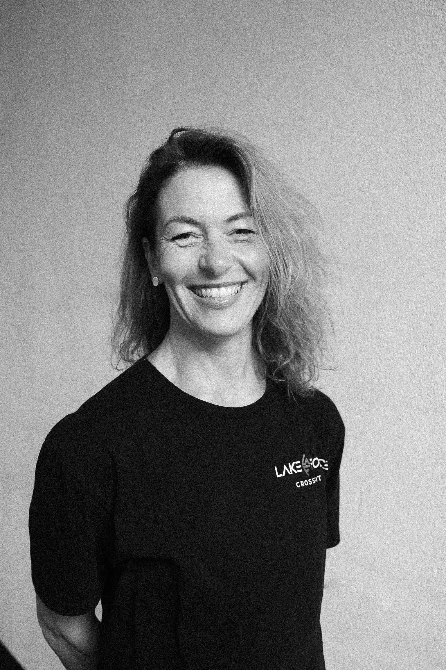 Frau beim Gewichtheben in einer Hocke in einem Fitnessstudio, mit einer Langhantel über dem Kopf.