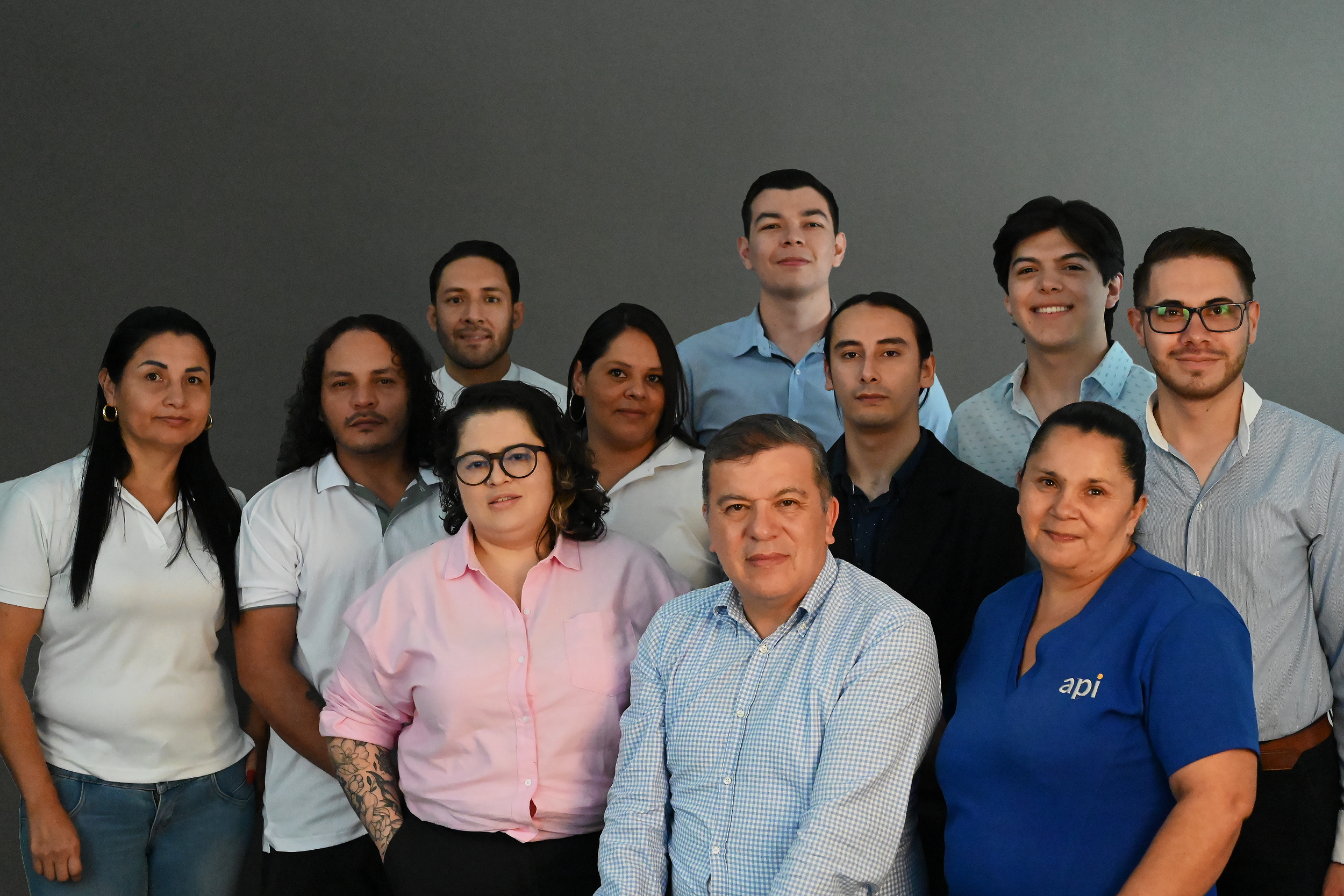 Group of diverse people posing indoors, some wearing casual attire, others in business casual clothing.