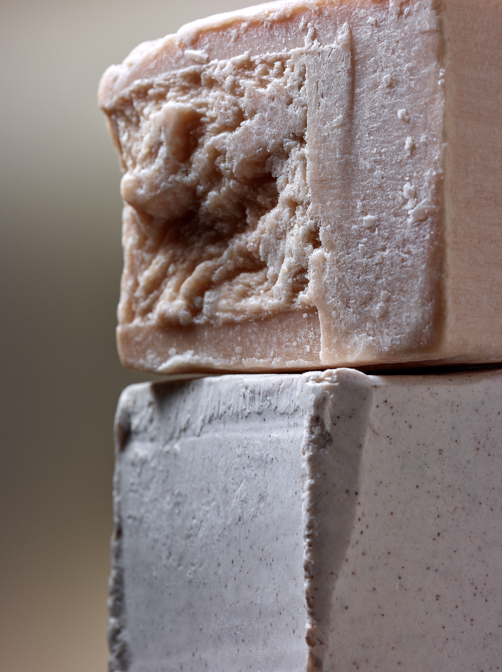 Image of two bars of soap, one on top of the other; one is light pink and the other is white with red dots.