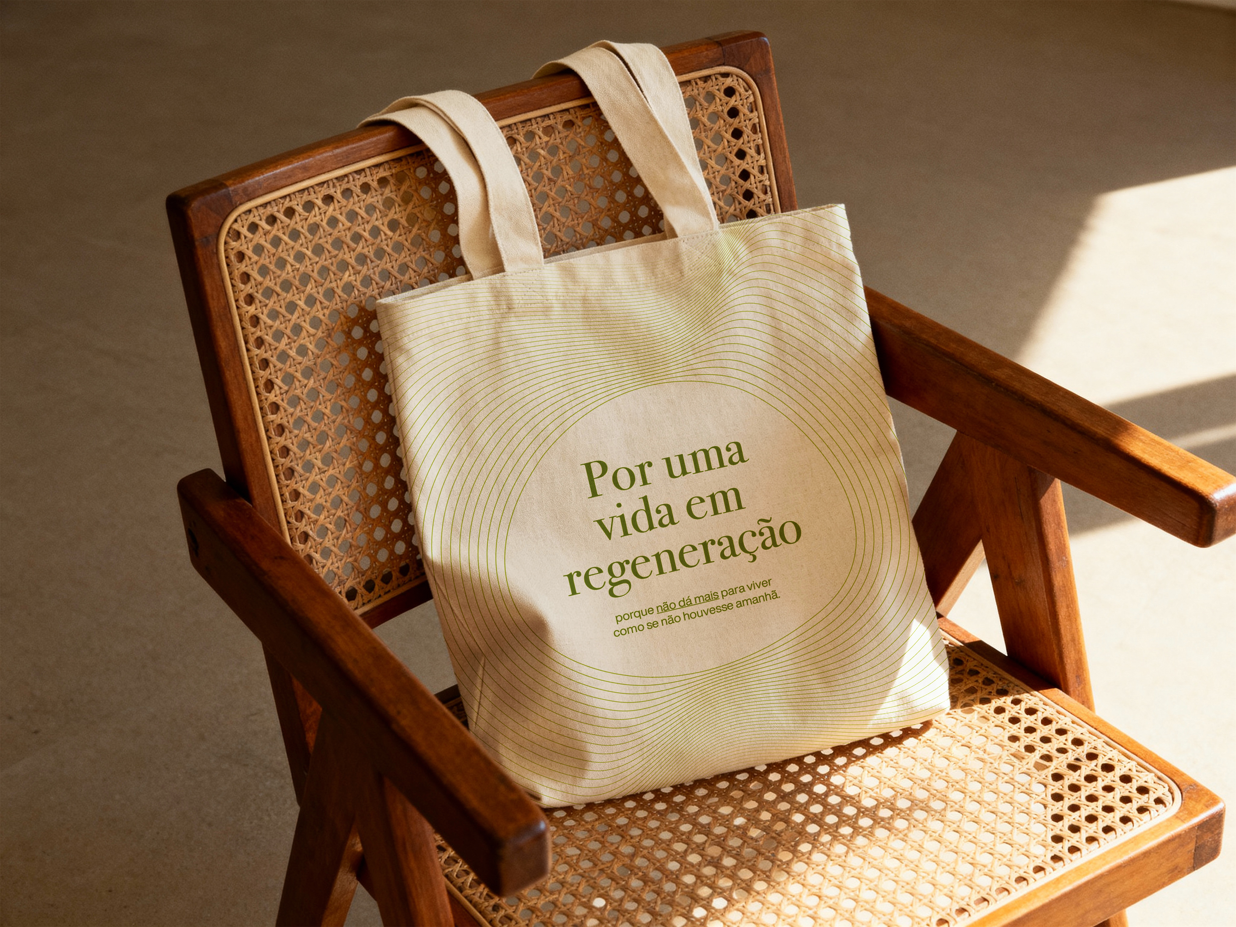A wooden chair with a straw seat, with a white cloth bag hanging from the backrest, bearing a message written in Portuguese.