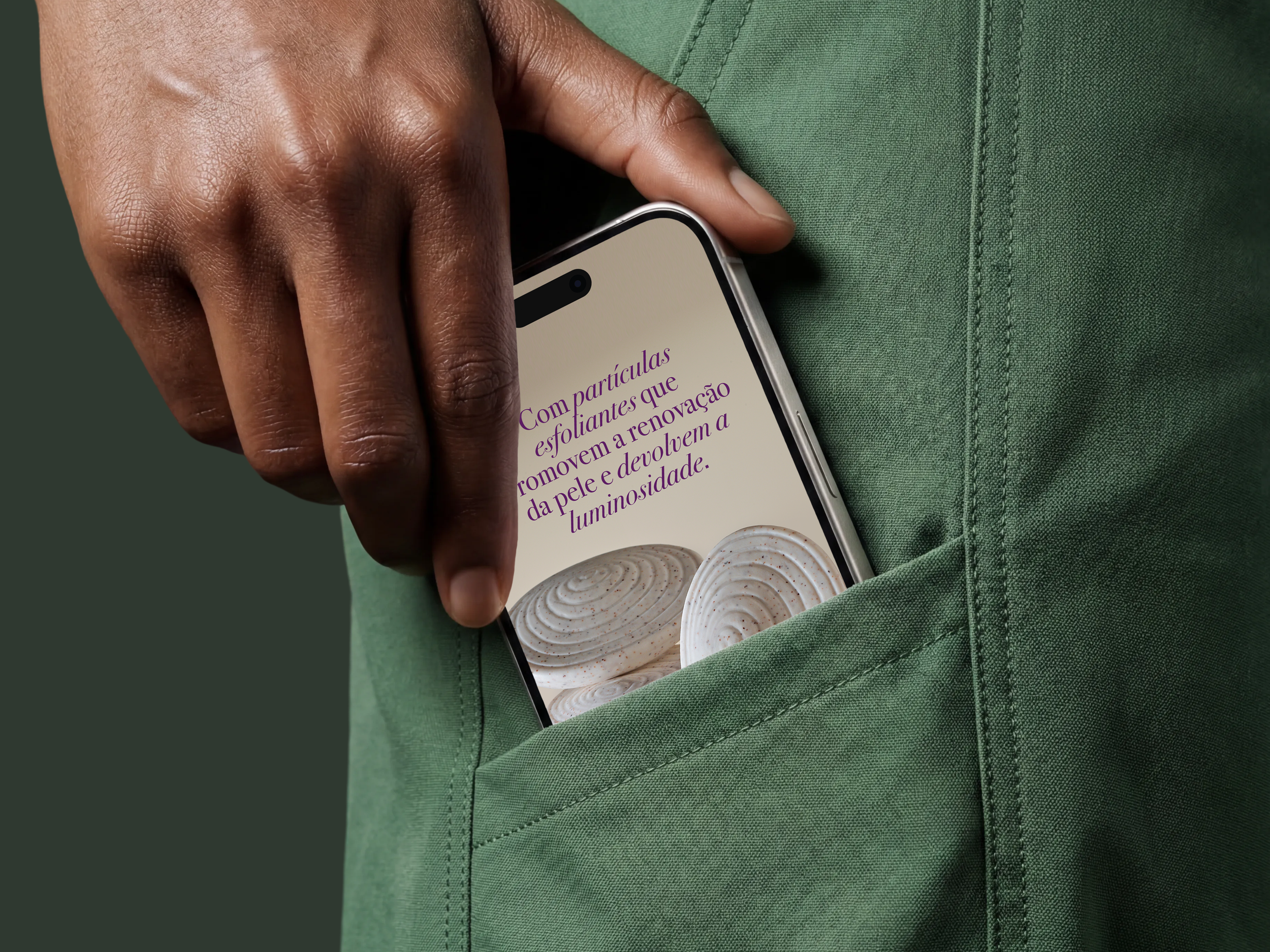 A person wearing a green T-shirt is holding a cell phone with a screen displaying text in Portuguese; the person's hand is resting on their shirt.