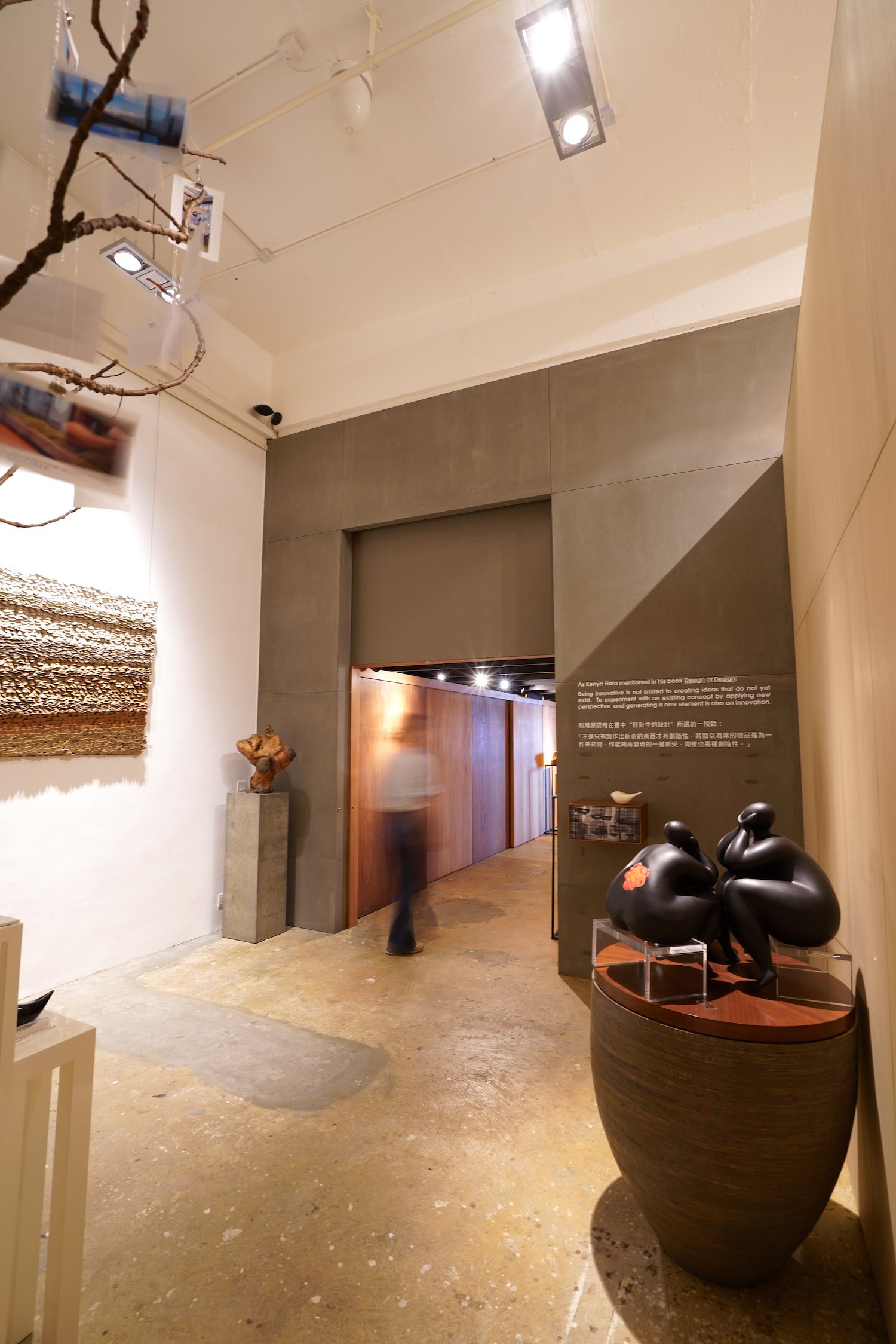 Interior of an art gallery with sculptures and woven wall art.