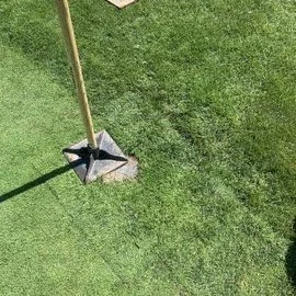 Lawn with a golf hole flag and a sand trap in a grassy area.