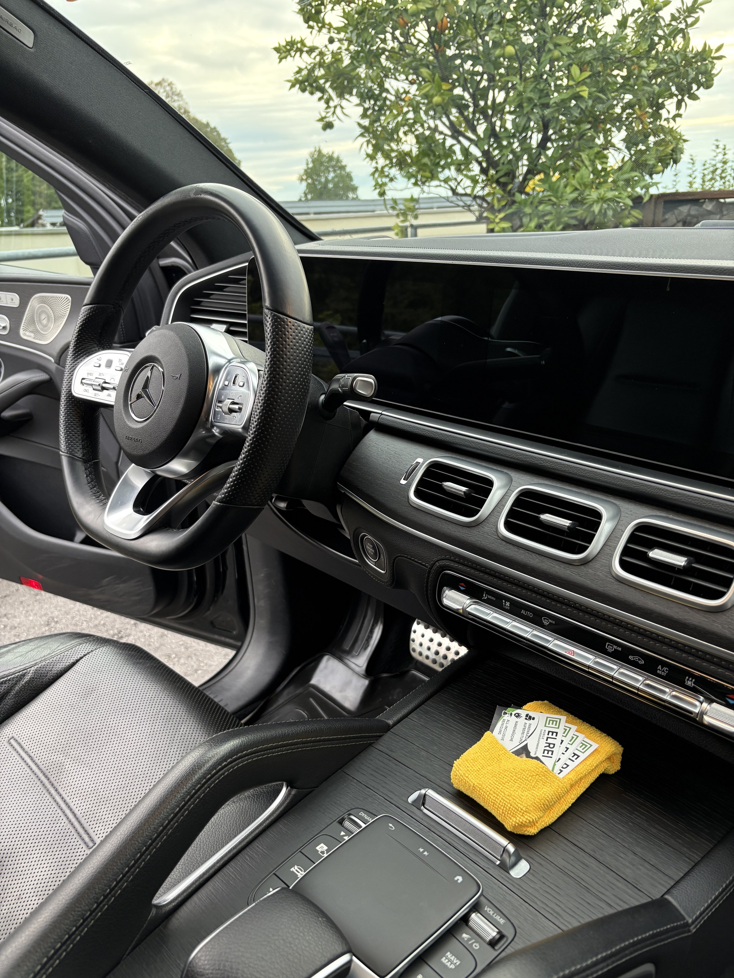 Innenansicht eines Autos, der Blick auf das Lenkrad und die Mittelkonsole mit einem gelben Reinigungstuch und Karten