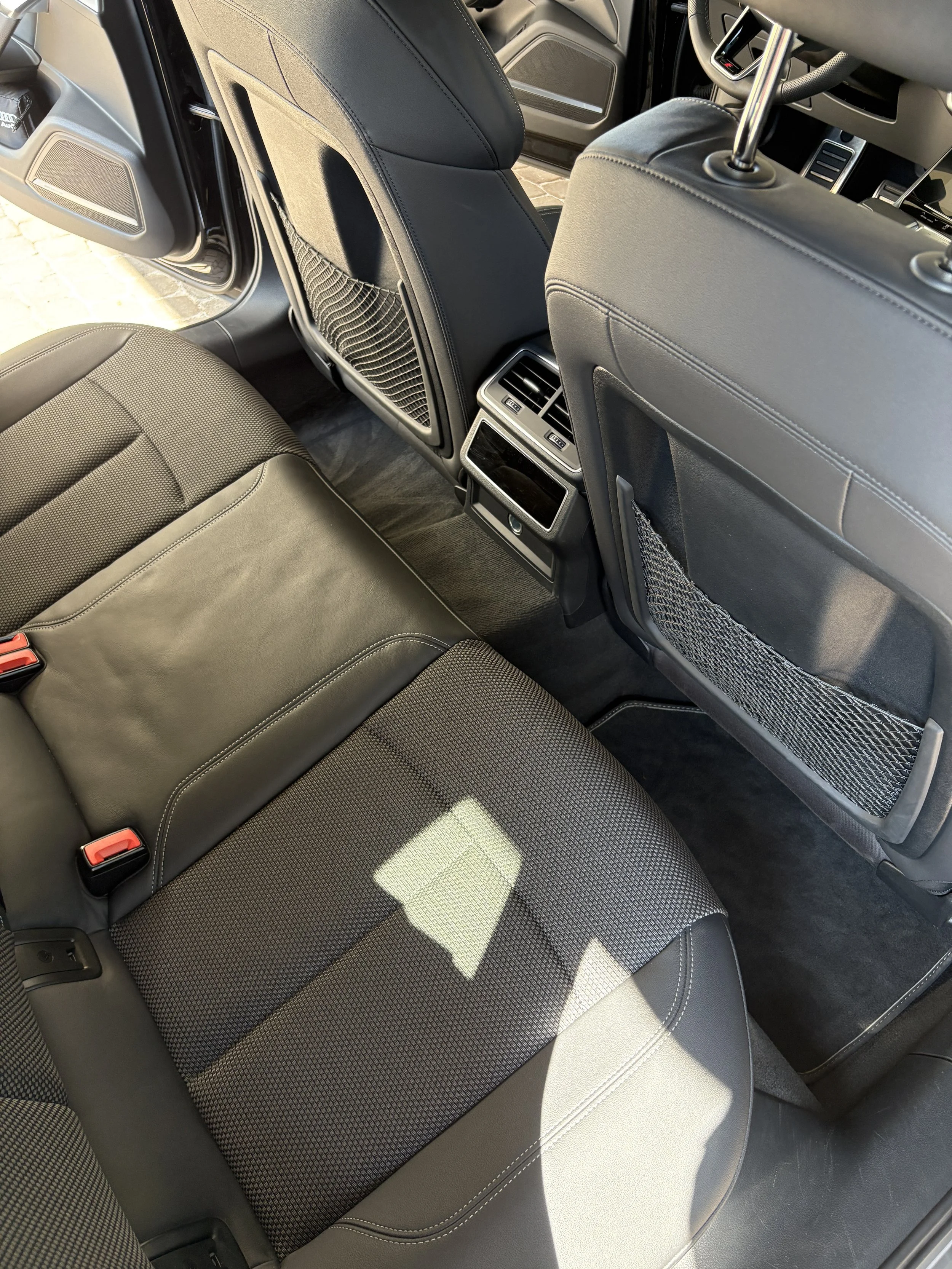 Die Rückseite der Vordersitze in einem Auto, mit Airbags, die in den Kopfstützen integriert sind, und Netzfächern an den Rückseiten der Vordersitze.