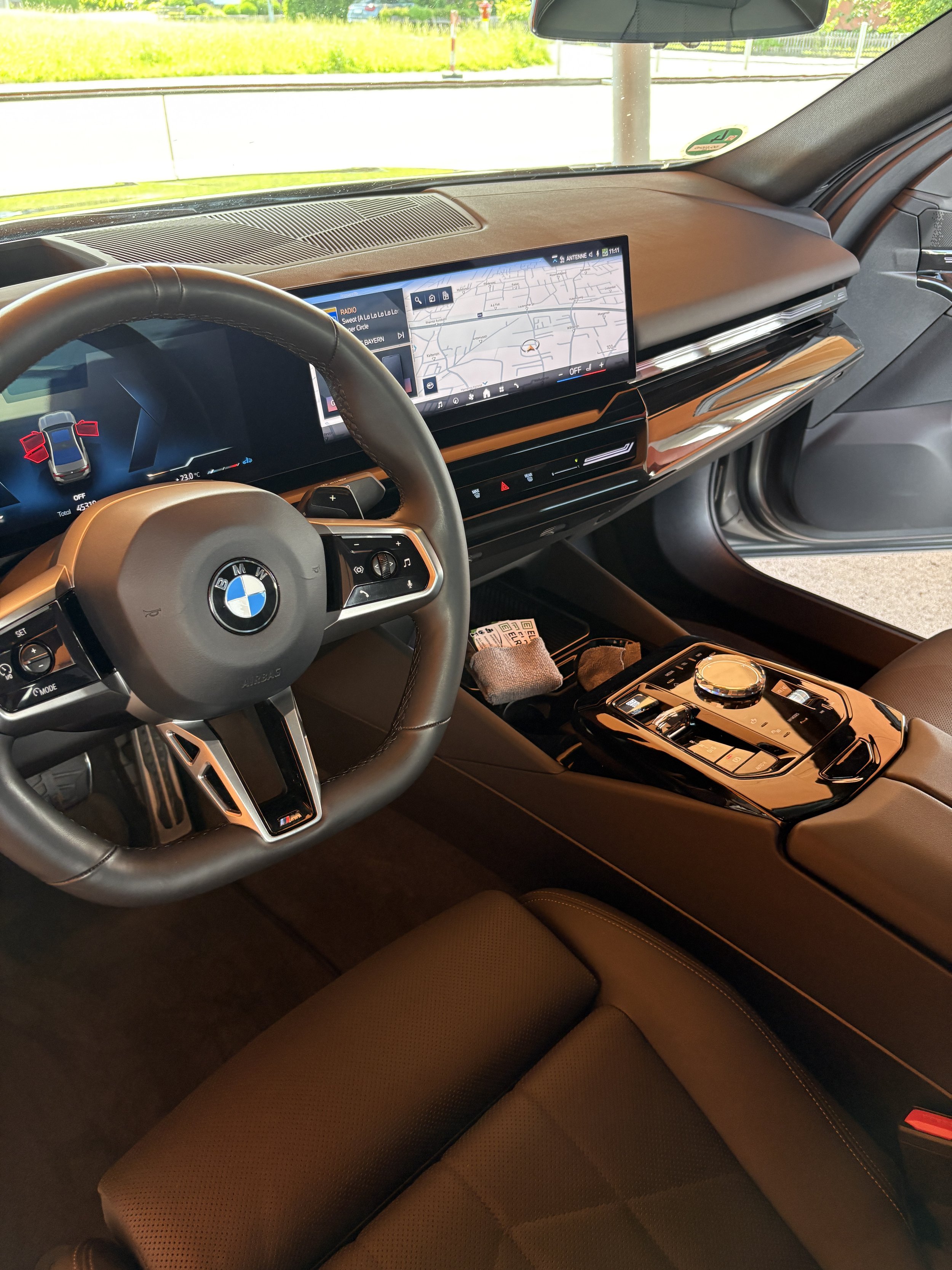 Innenraum eines BMW-Fahrzeugs mit Display, Lenkrad und Sitz.