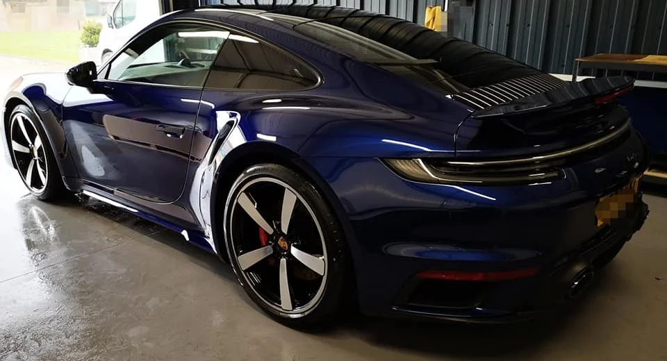 A dark blue Porsche sports car parked inside a garage.