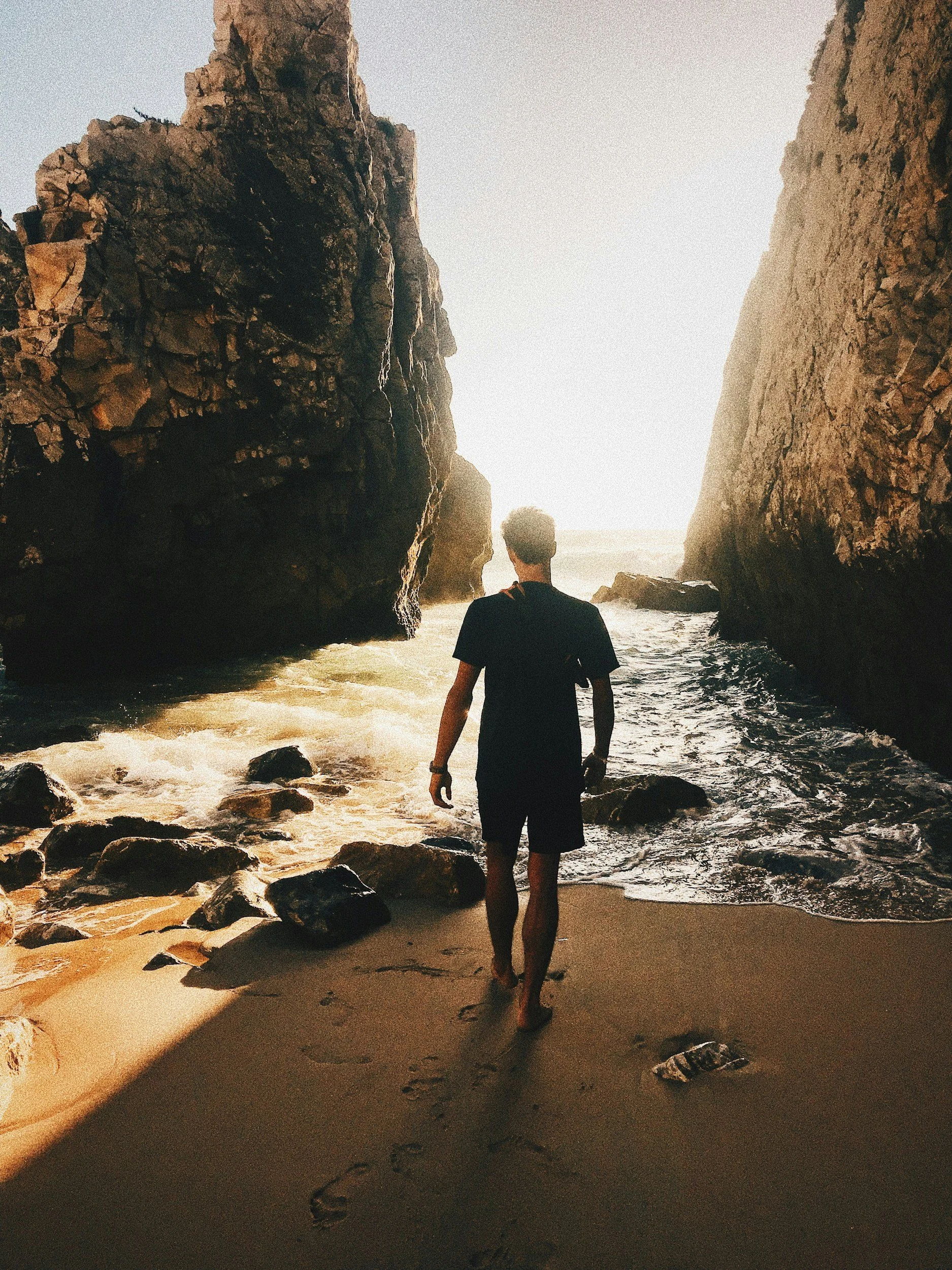 Man walking along a rocky beach, representing health, vitality, wellness, and longevity.