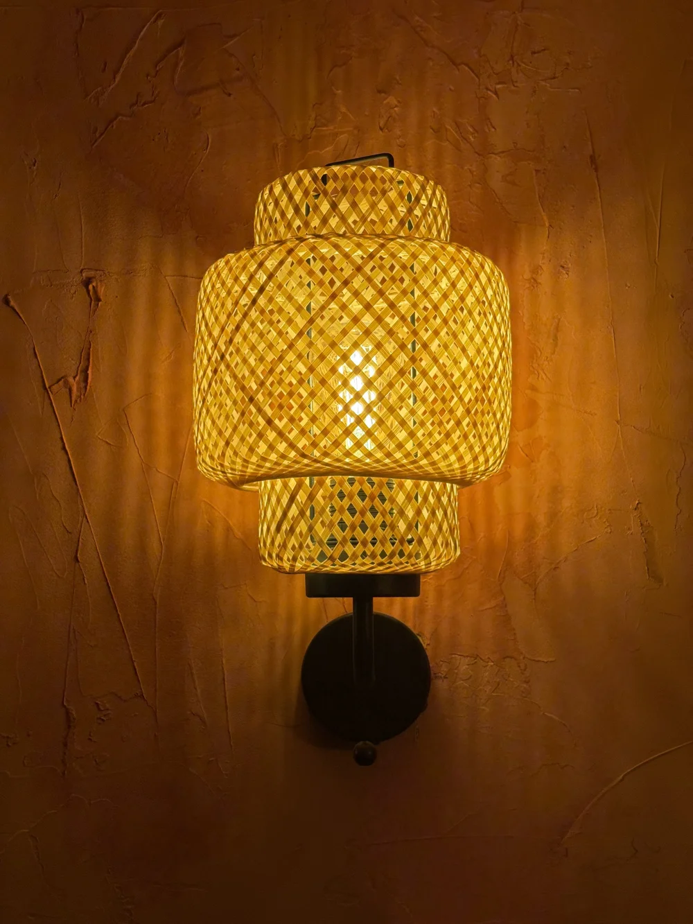 A woven wall light casting a warm glow
