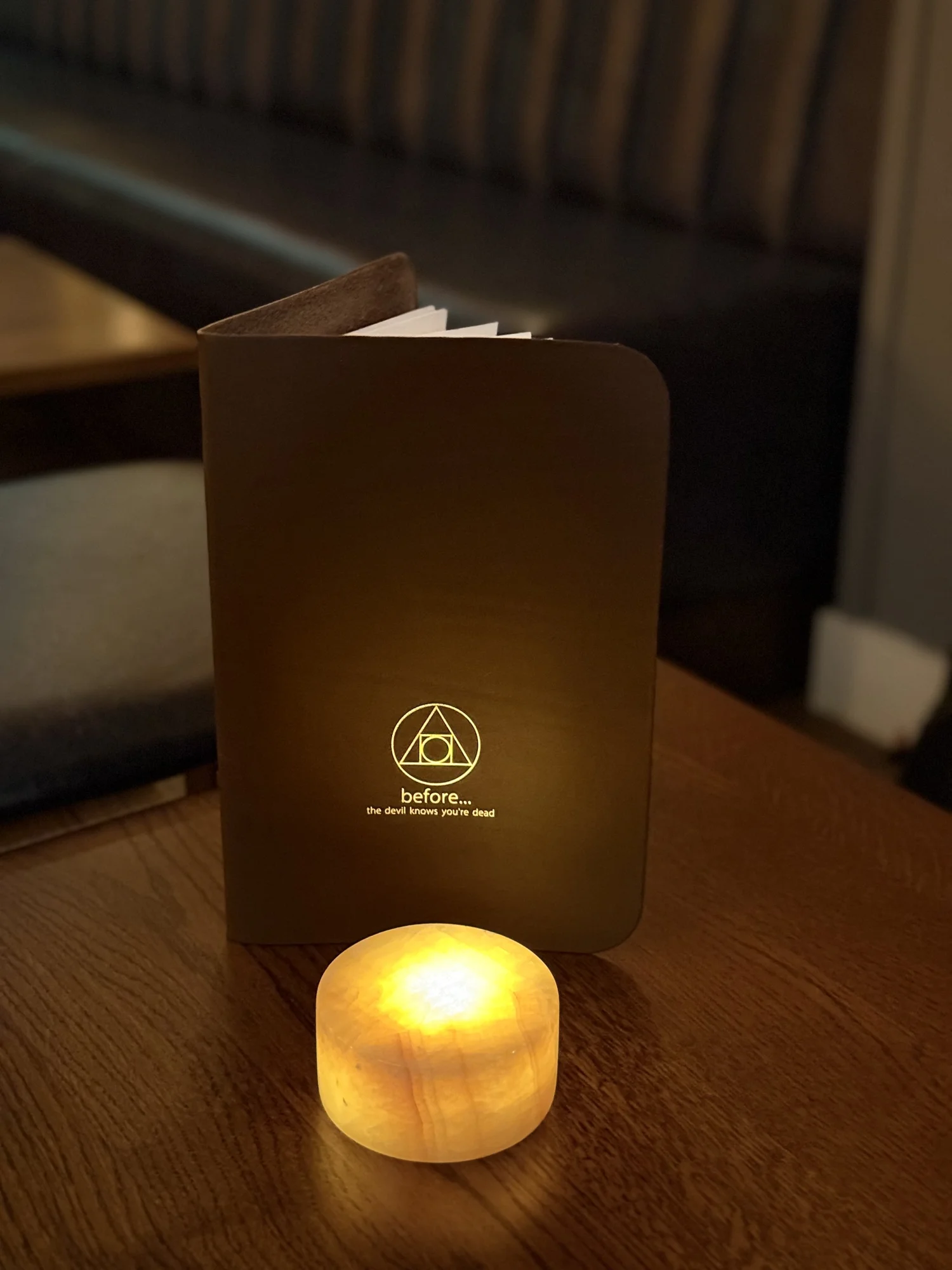 A warm candle glowing beside the before menu on a wooden table