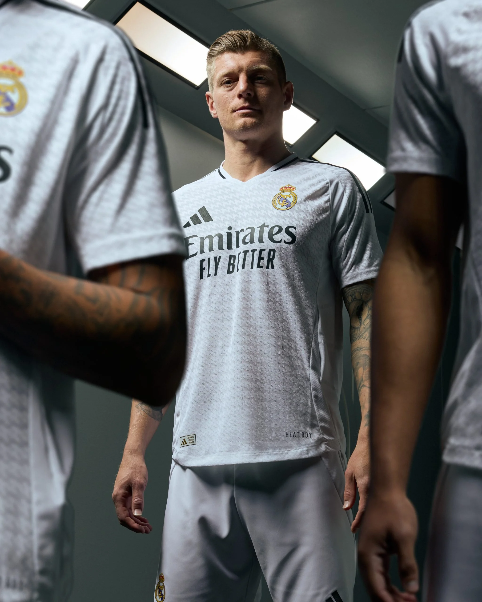 Jugadores del Real Madrid en el vestuario, con uniforme blanco adidas, en una postura pensativa.