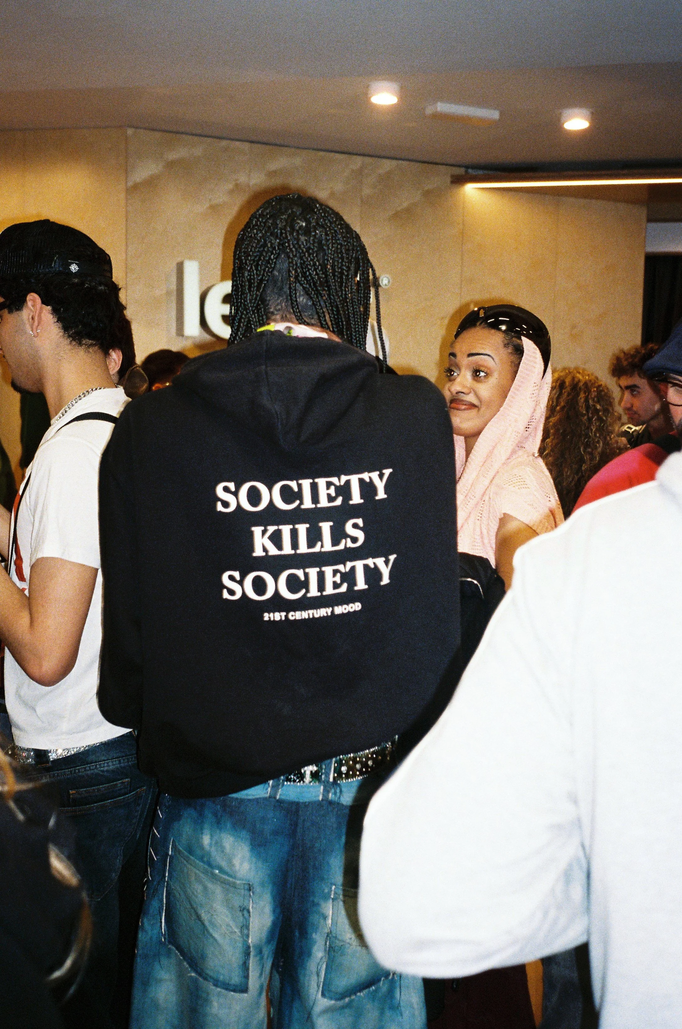 Apertura local Legit Barcelona - Persona con sudadera negra que dice 'Society kills society' en la espalda, en un evento con varias personas.