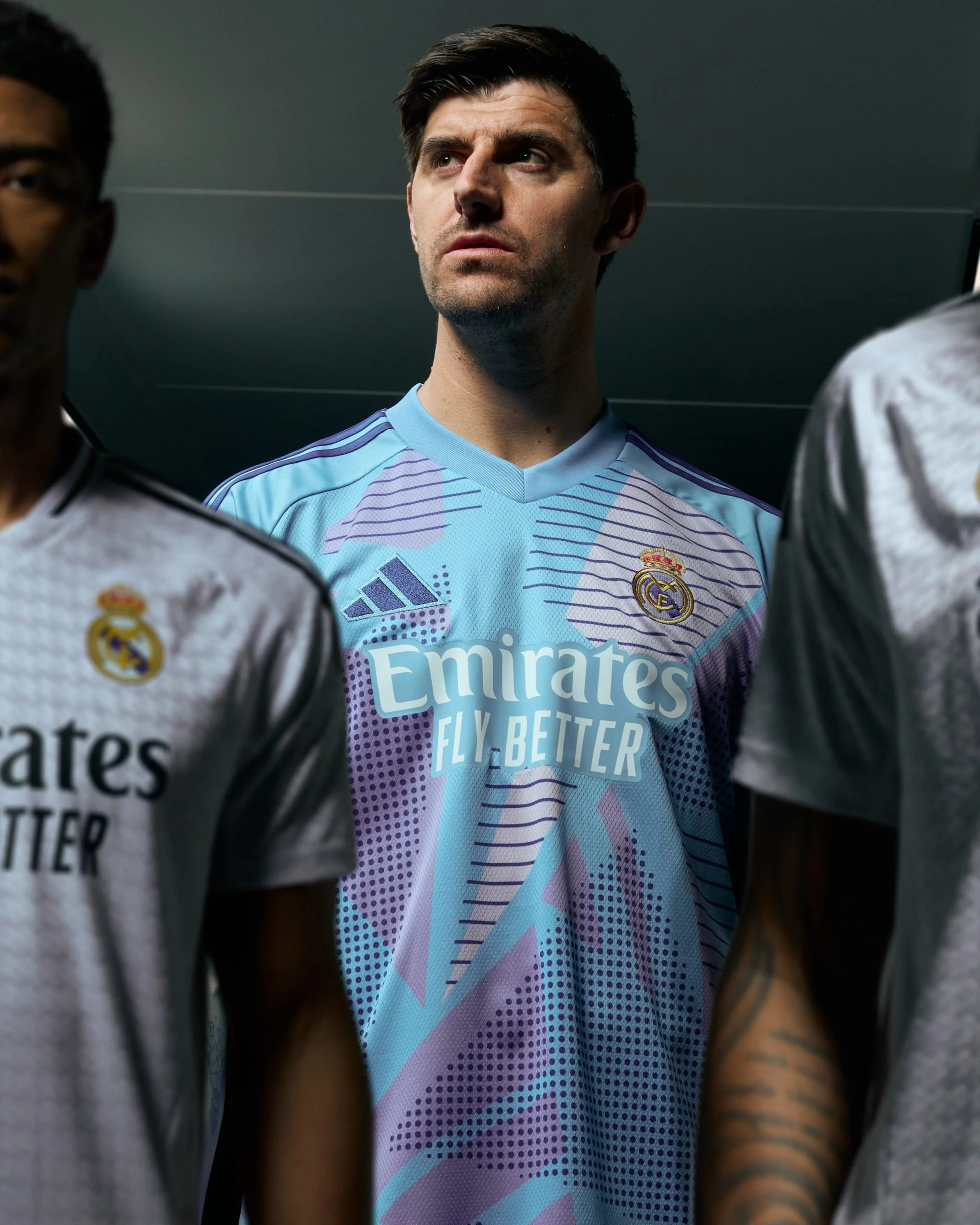 Un jugador de fútbol de espaldas con camiseta de adidas Real Madrid y un hombre con camiseta del Real Madrid entre sus compañeros