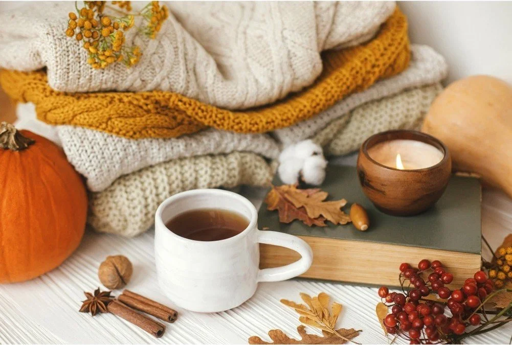 Cozy autumn arrangement with a white mug, pumpkin, and knit sweaters in a tidy home.