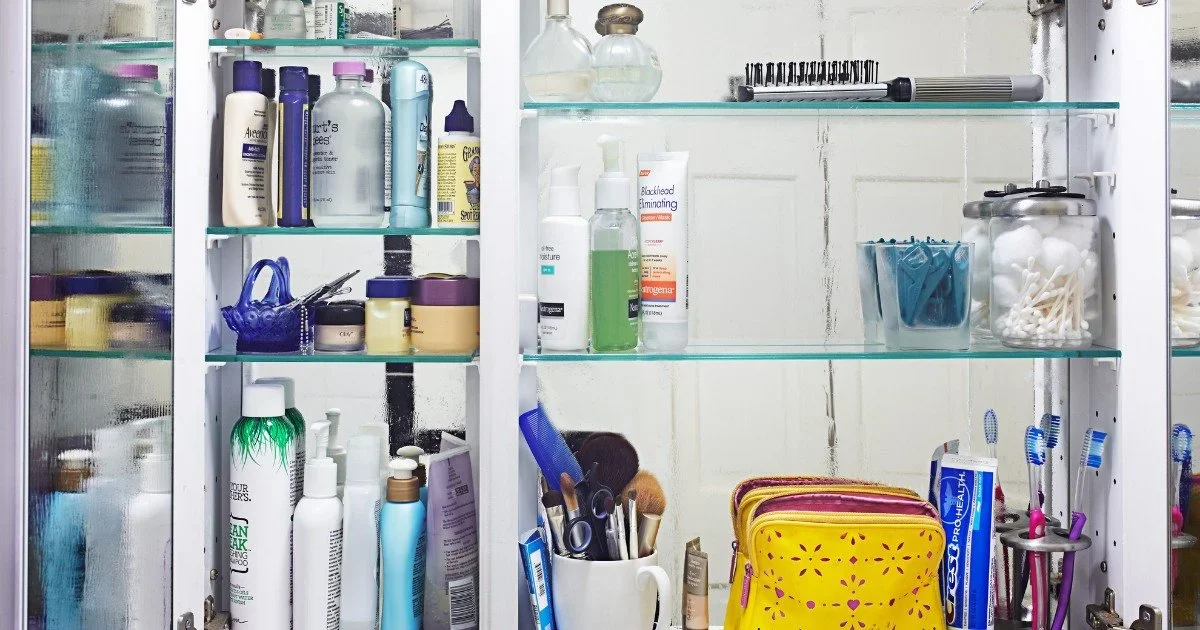 Organized bathroom medicine cabinet with glass shelves, skincare products, and a yellow travel bag.