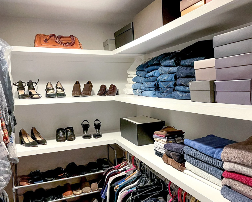 Professional closet organization by Organizing Etc in Kansas City, featuring white L-shaped shelves with neatly folded jeans, shoes, and storage boxes.