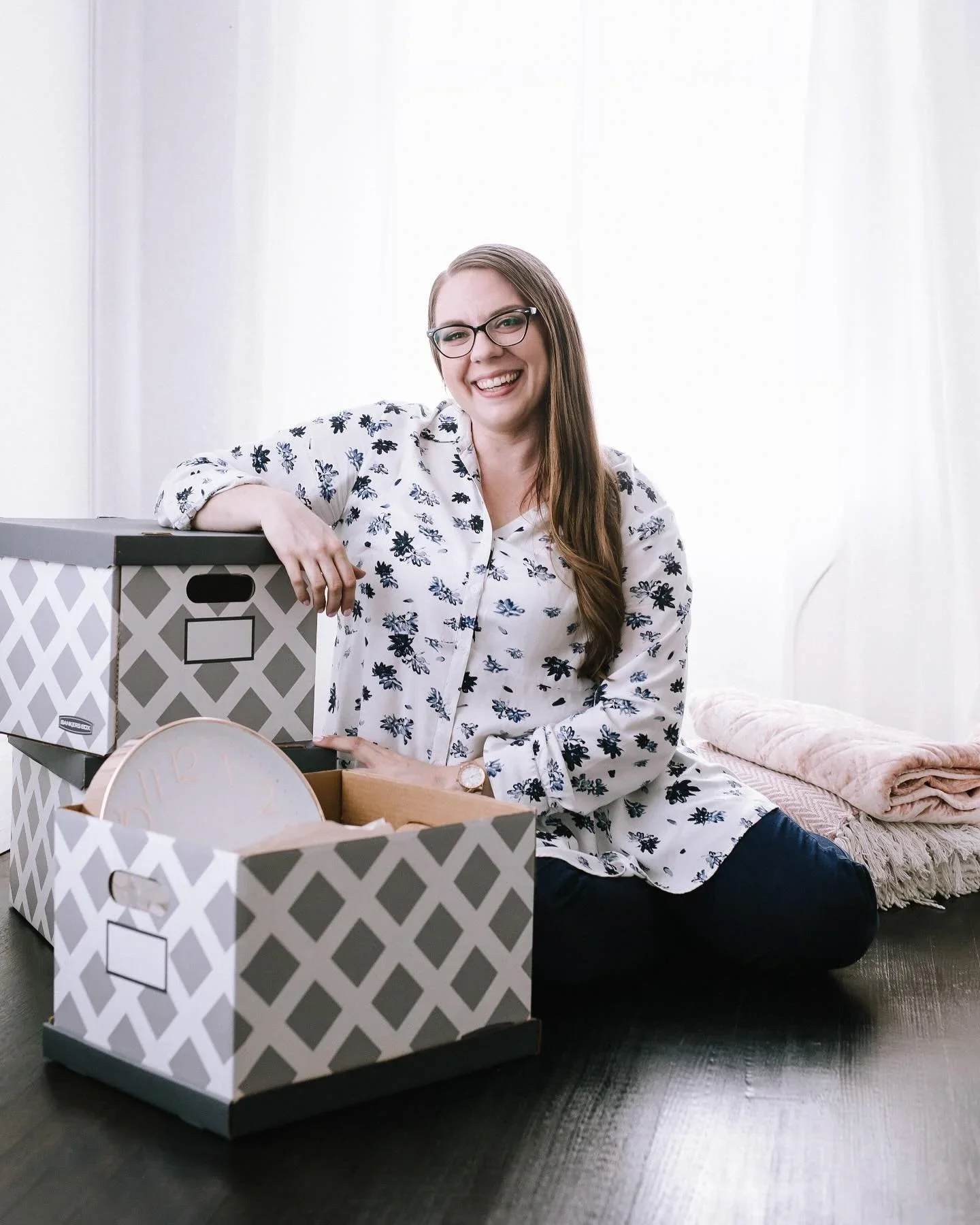 Professional organizer Sarah Brent, founder of Practical Harmony, smiling with decorative storage bins in her Bloomington, IL studio.