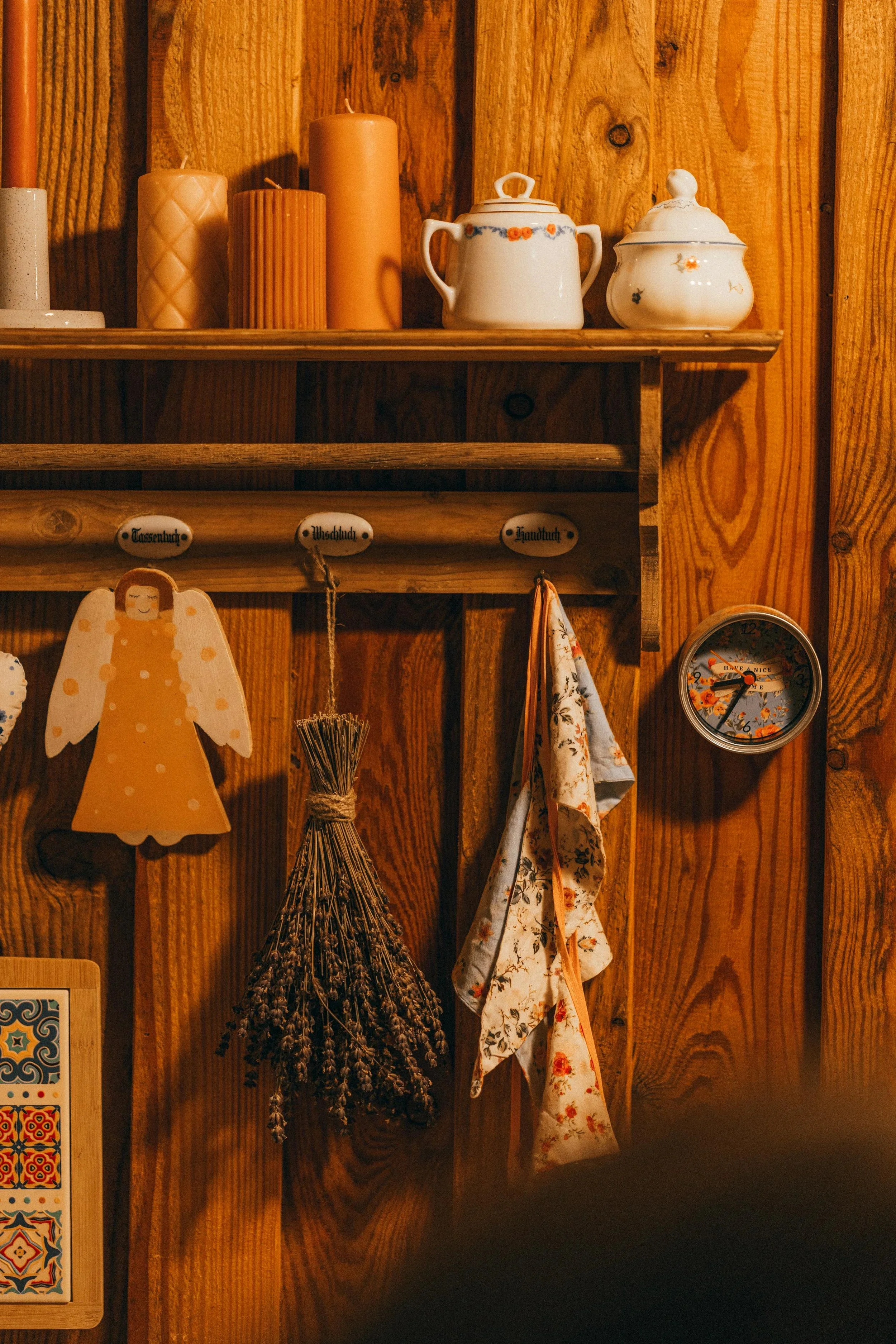Rustic kitchen organization by Michele Makes Space in Columbus, featuring a wooden wall shelf with candles, ceramic jars, and hanging dried lavender.