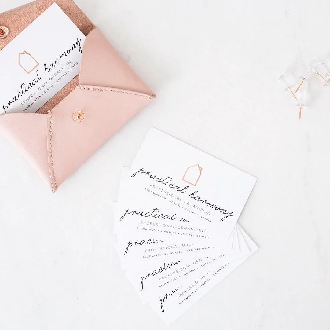 Practical Harmony business cards in a pink leather pouch on a white marble surface.