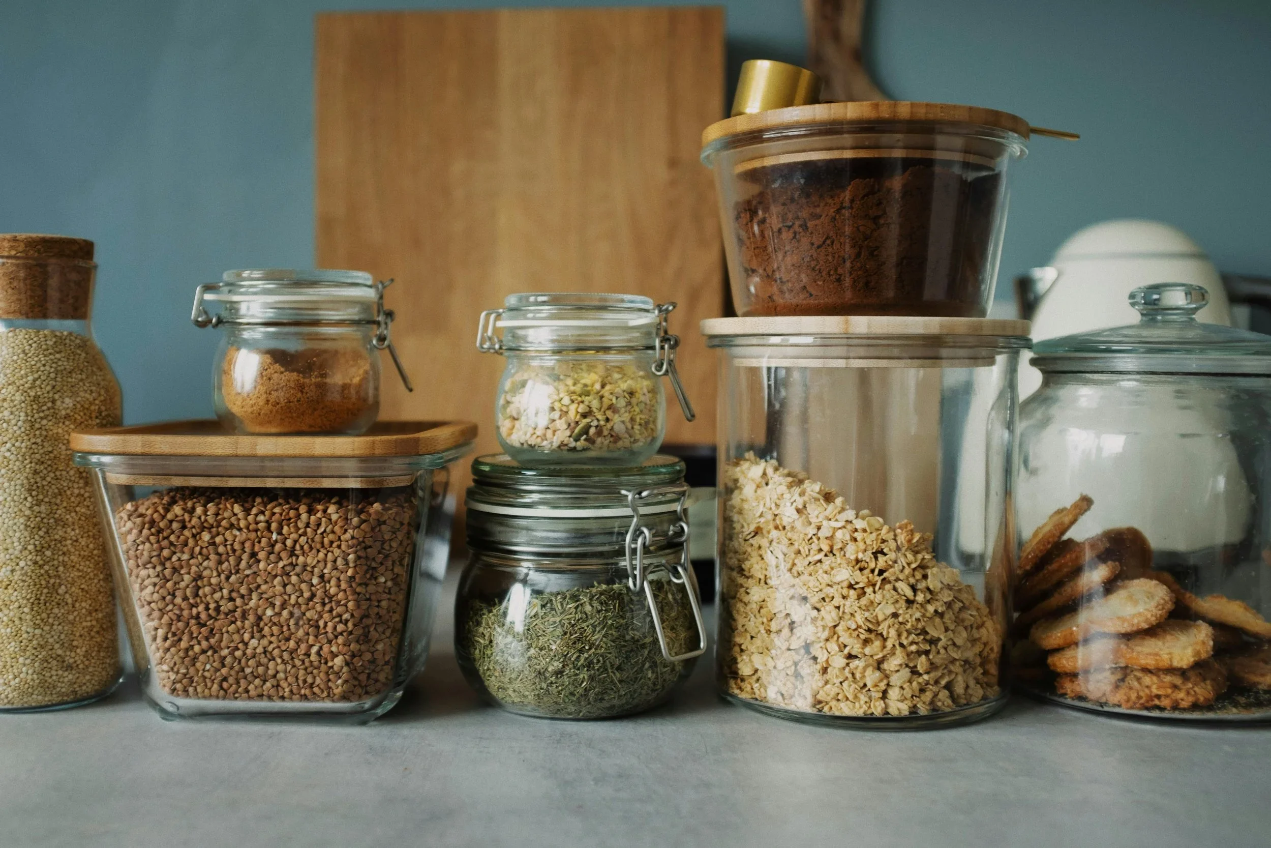 Organized kitchen counter with various glass storage jars filled with grains, oats, and snacks.