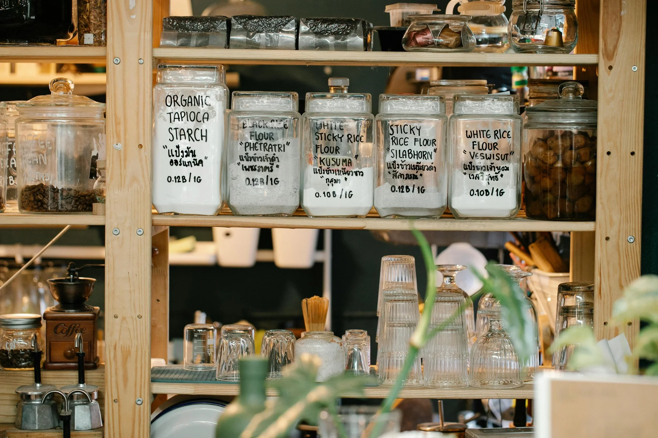 Labeled glass jars of organic flours and starches neatly arranged on wooden pantry shelves by Endlessly Organized Now in Southlake, TX.