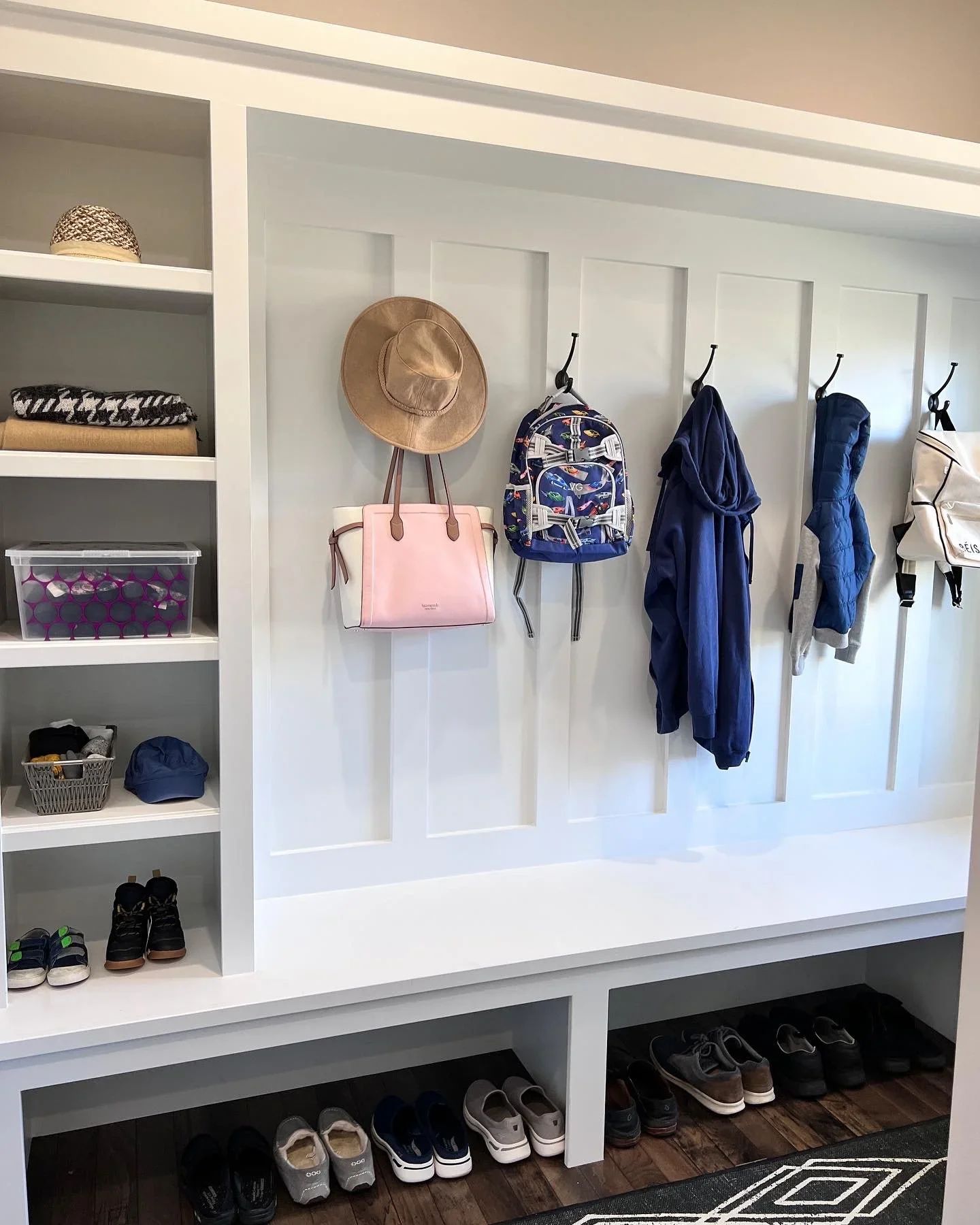 Organized white built-in mudroom lockers by Custom Order Home Organizing in the Quad Cities, featuring coat hooks, storage bins, and shoe cubbies.