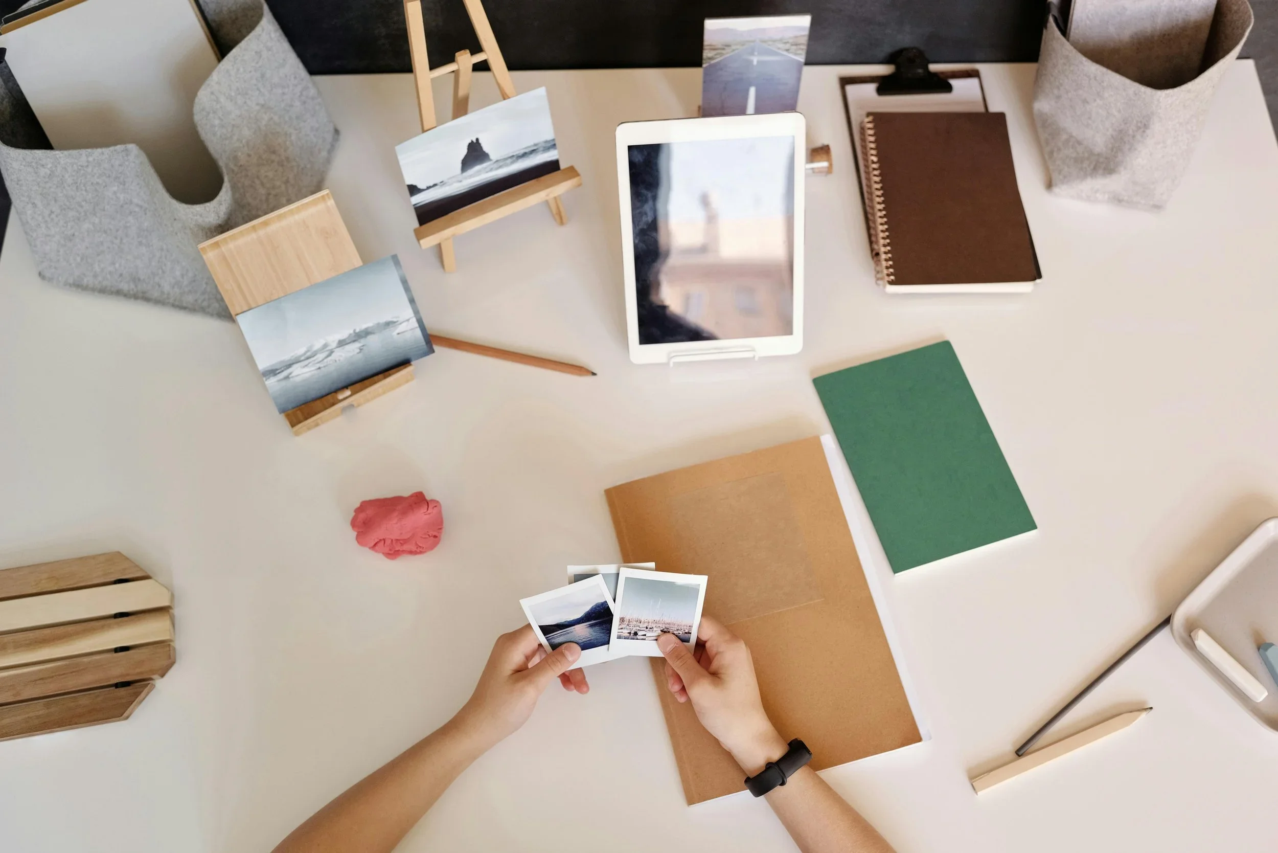 Professional photo and memory organization by Endlessly Organized Now in Southlake, TX, featuring hands sorting printed pictures on a minimalist white desk with a tablet and notebooks.