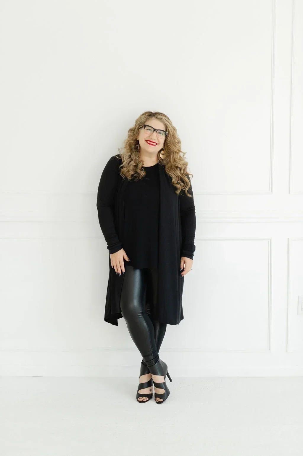 Melissa Klug, CEO of Pro Organizer Studio, smiling in an all-black outfit against a white paneled wall.