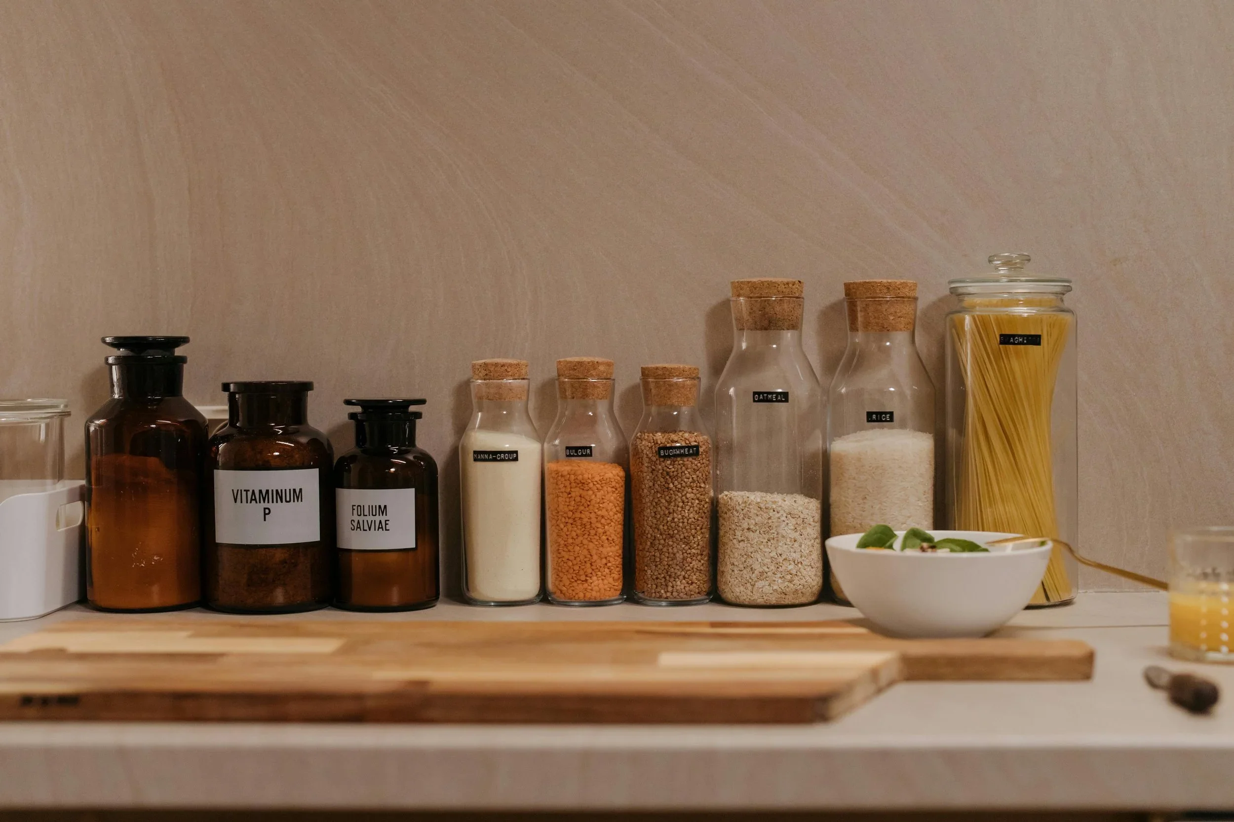 Organized kitchen counter with labeled glass spice jars, cork stoppers, and dry goods.