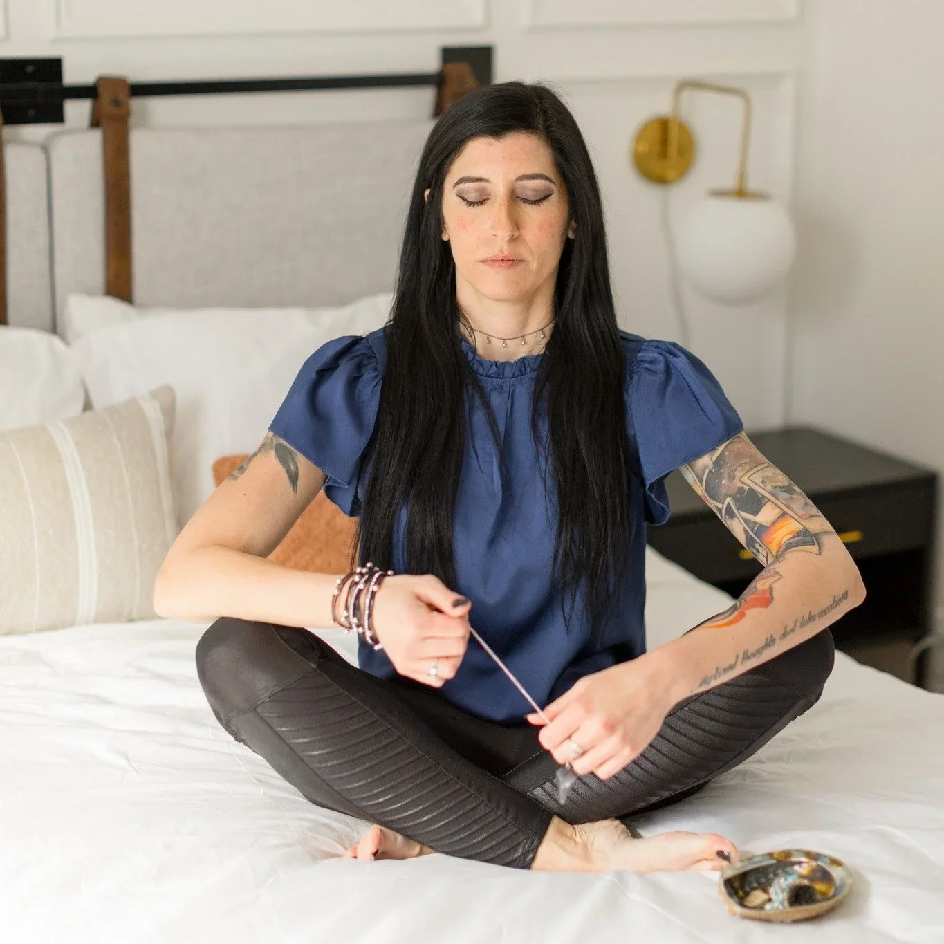 Professional organizer Chelsea Lewis, founder of Third Eye Tidy in Denver, meditating in a bright, modern bedroom.