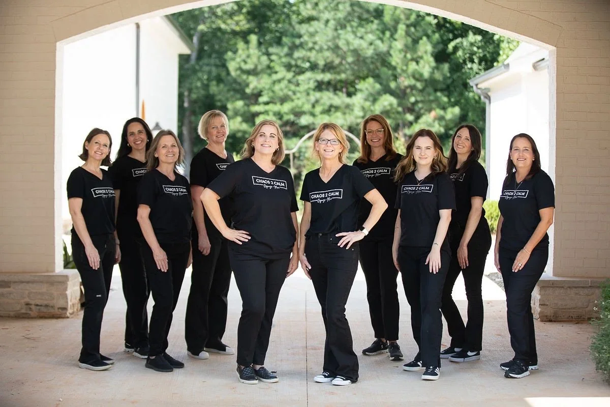 The professional home organizing team of Chaos 2 Calm in Atlanta, featuring owners April and Kelly with their staff in branded black t-shirts.