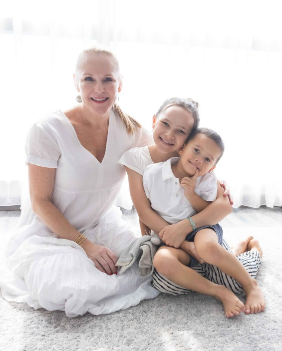 Professional organizer Angela Nguyen smiling with two children in a bright room.