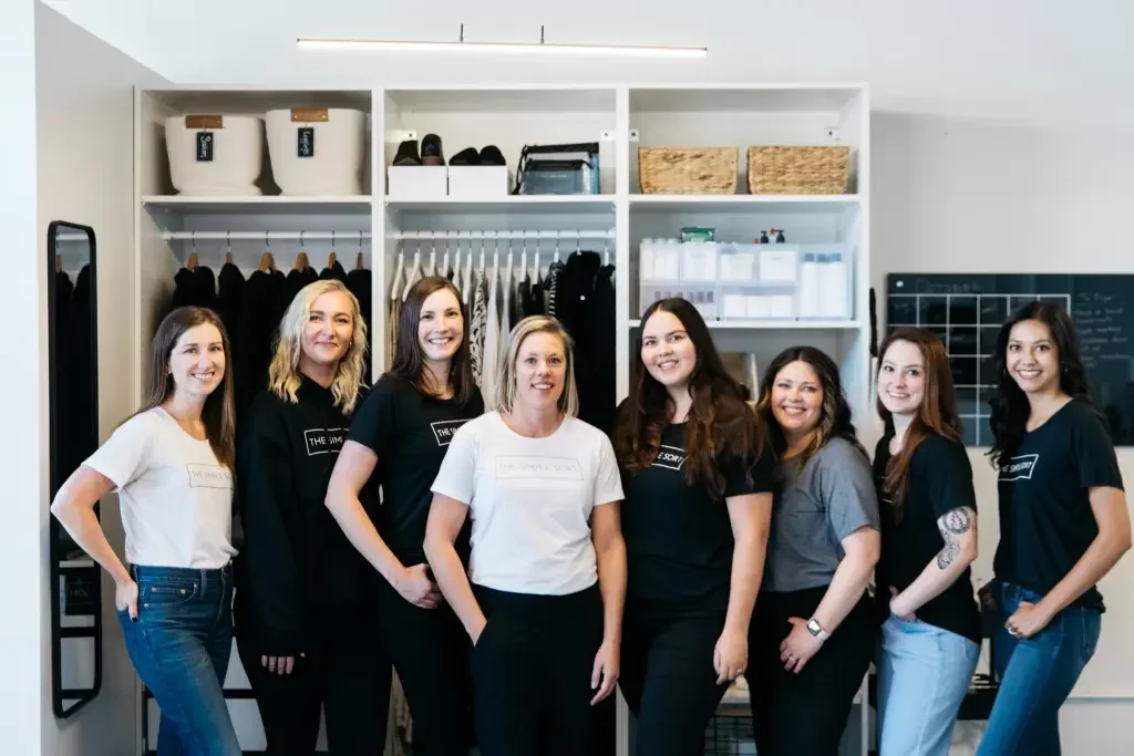 The Simple Sort professional organizing team standing in front of an organized white closet.