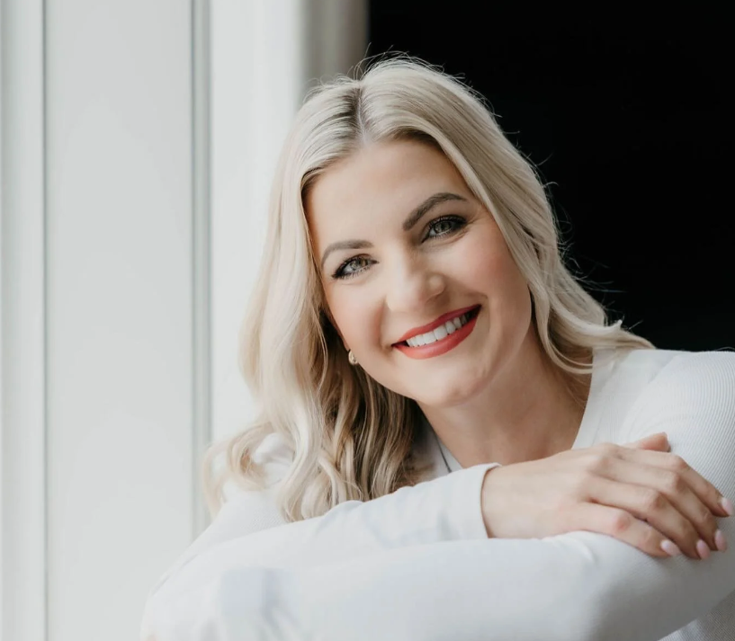 Holli, founder of Holli & Co. professional home organizing, smiling for a professional portrait in a white top.