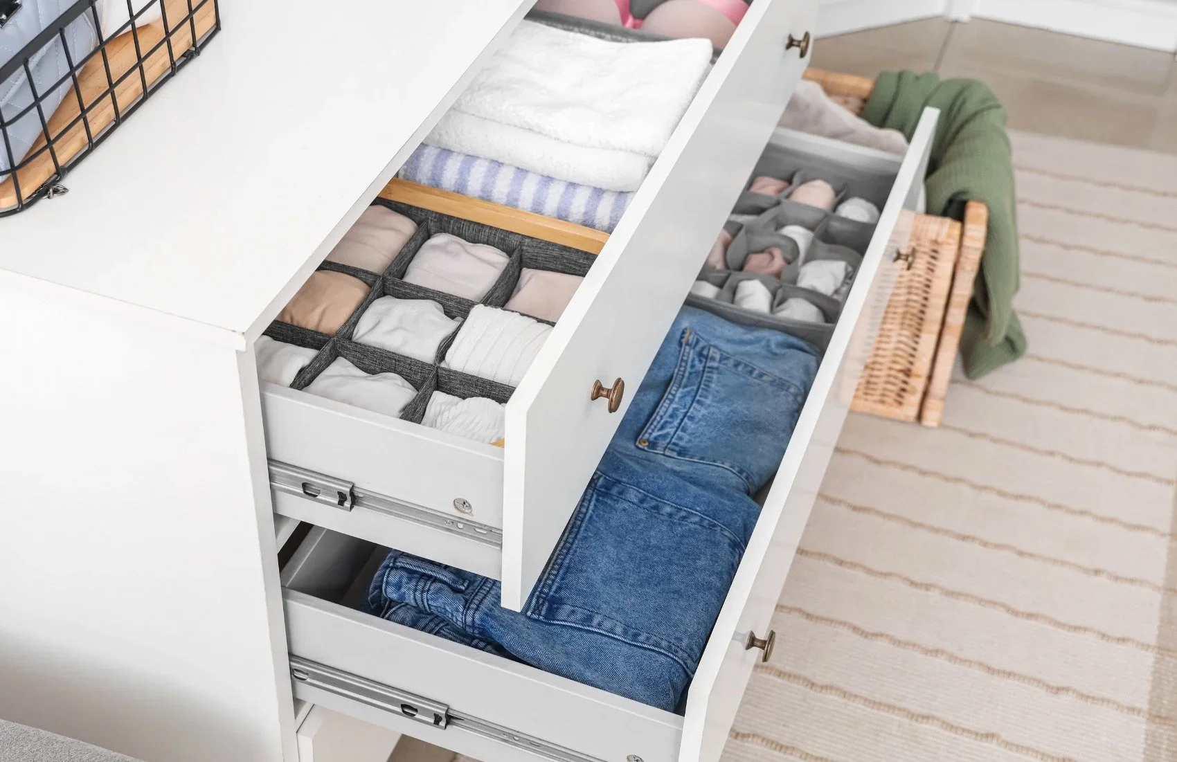 Organized white dresser drawers with file-folded clothing and fabric drawer dividers.