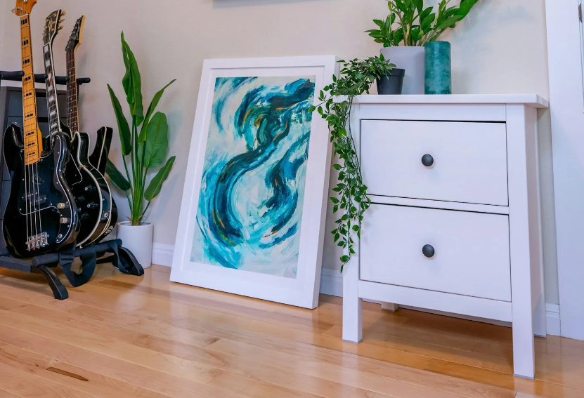 Styled home organization in Seattle by like BEGETS like, featuring guitars, blue abstract art, and a white nightstand with plants.