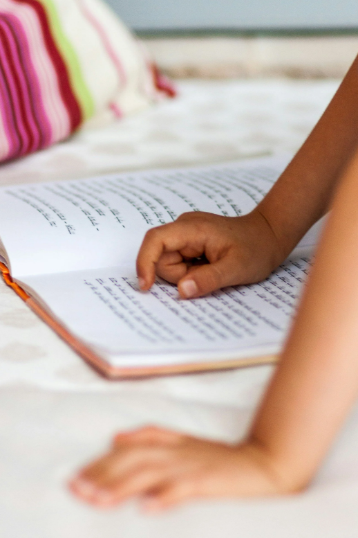 A young child's hands resting on an open book, showcasing a peaceful home reading routine by Amy Louise Organizing.