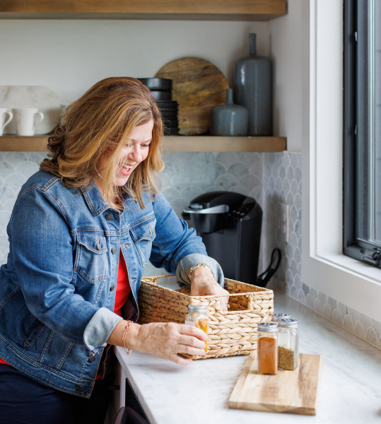 Professional organizer Barb organizing kitchen spices in a woven basket.