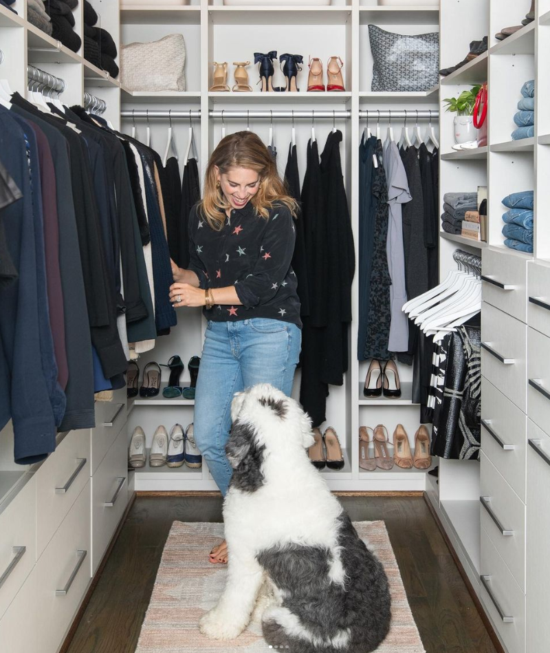 Professional organizer reviewing a custom walk-in closet with a sheepdog sitting nearby.