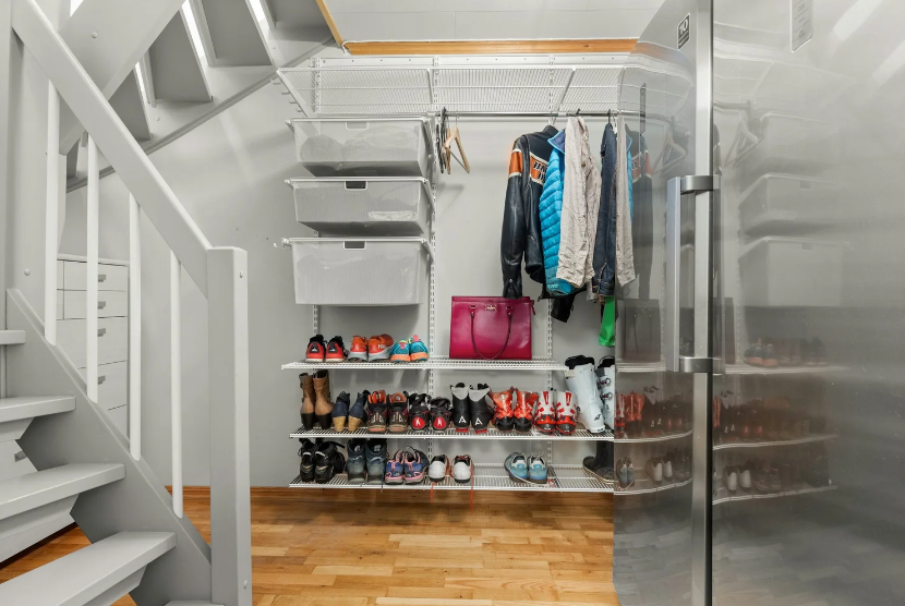 An organized mudroom by The Simple Sort in Colorado Springs, featuring Elfa-style shelving for shoes, bins, and hanging jackets under a staircase.