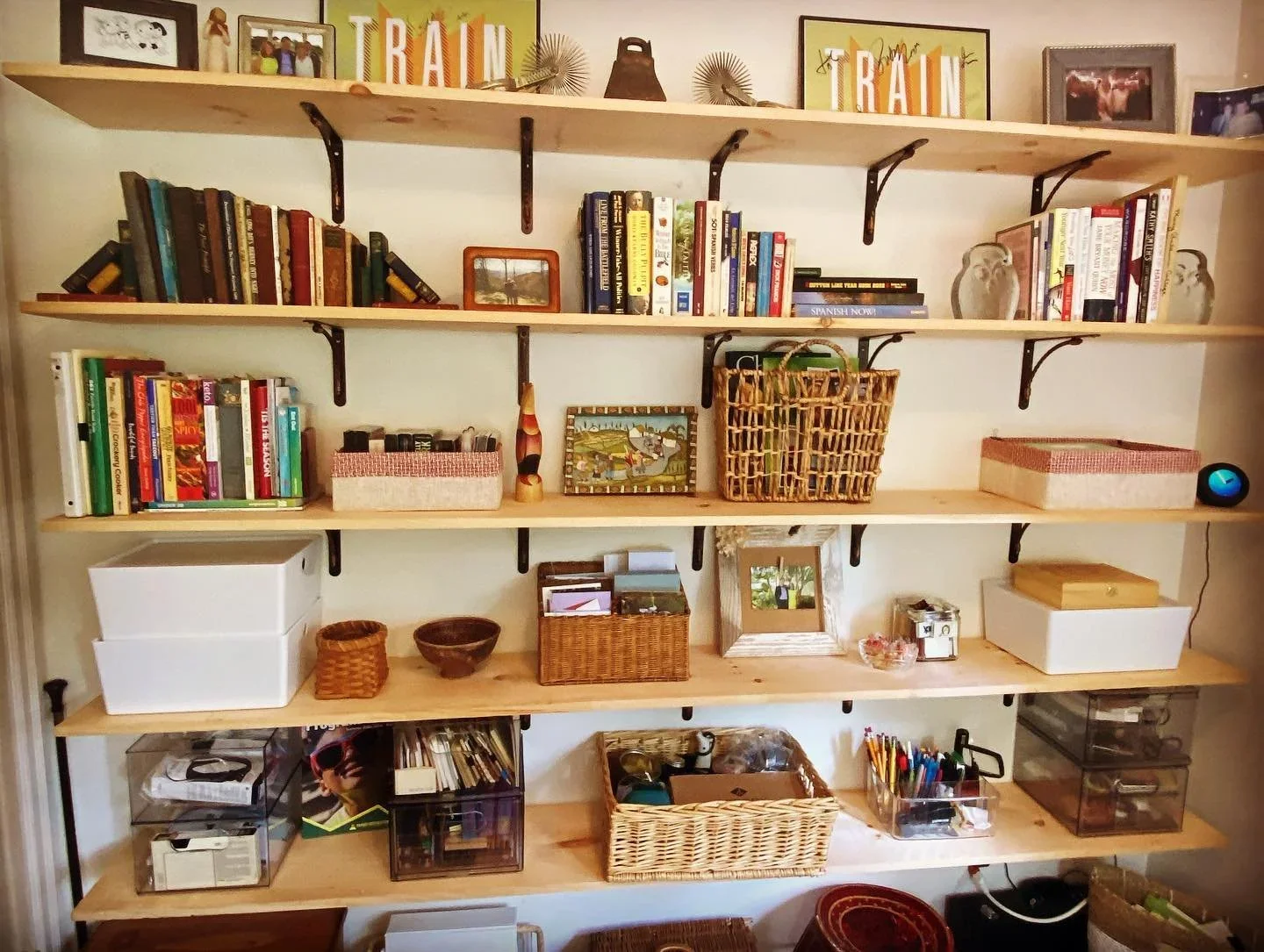 Functional wall-mounted wood shelving organized with books, woven baskets, and office supplies.