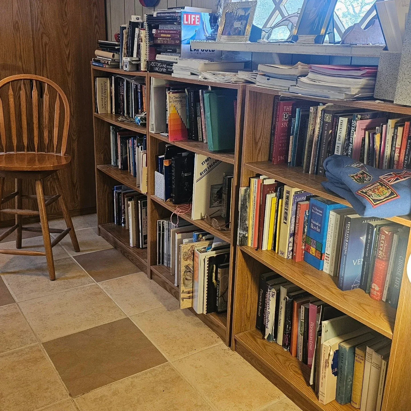 Cluttered wooden bookshelves filled with stacks of books and papers, representing a space ready for professional organization in Colorado Springs.